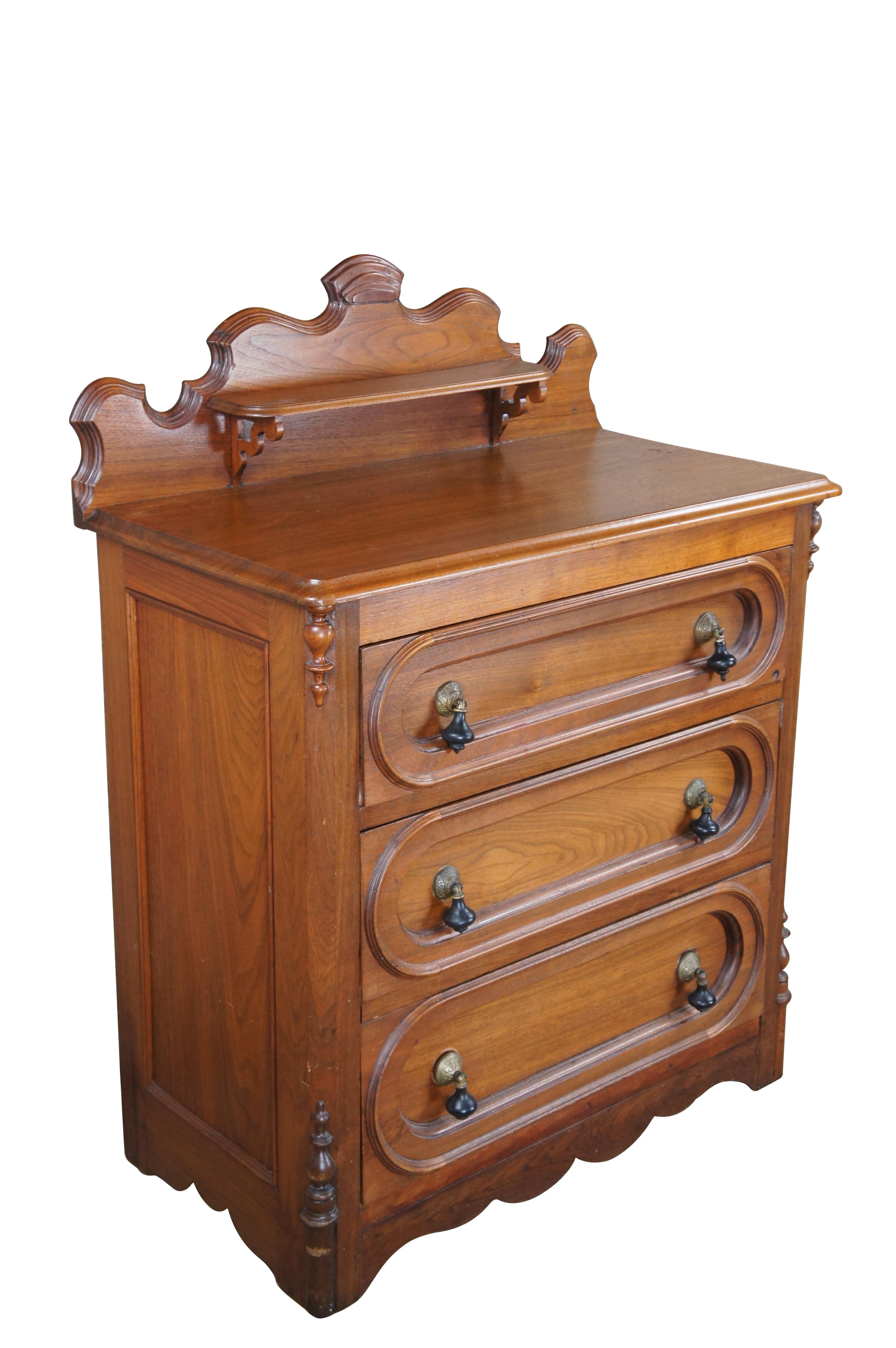 Antique Victorian chest of drawers / dresser.  Made of walnut featuring three paneled drawers with brass / ebonized tear drop hardware and ornate serpentine backsplash with shelf.

Dimensions:
33.5
