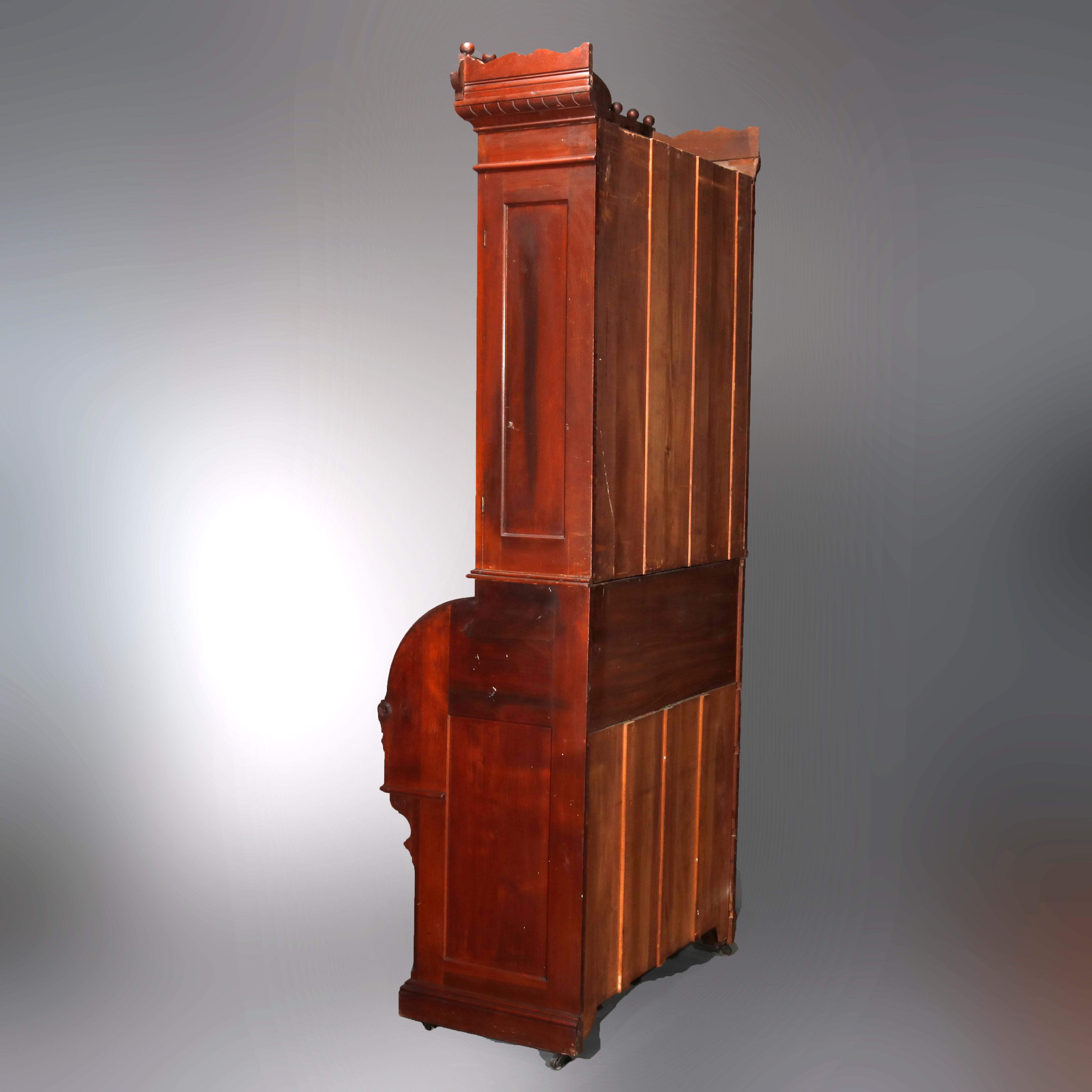 An antique Victorian Eastlake barrel roll secretary offers walnut construction with upper double door bookcase having foliate carved crest and surmounting desk and drawers and storage compartment having carved foliate decoration, circa