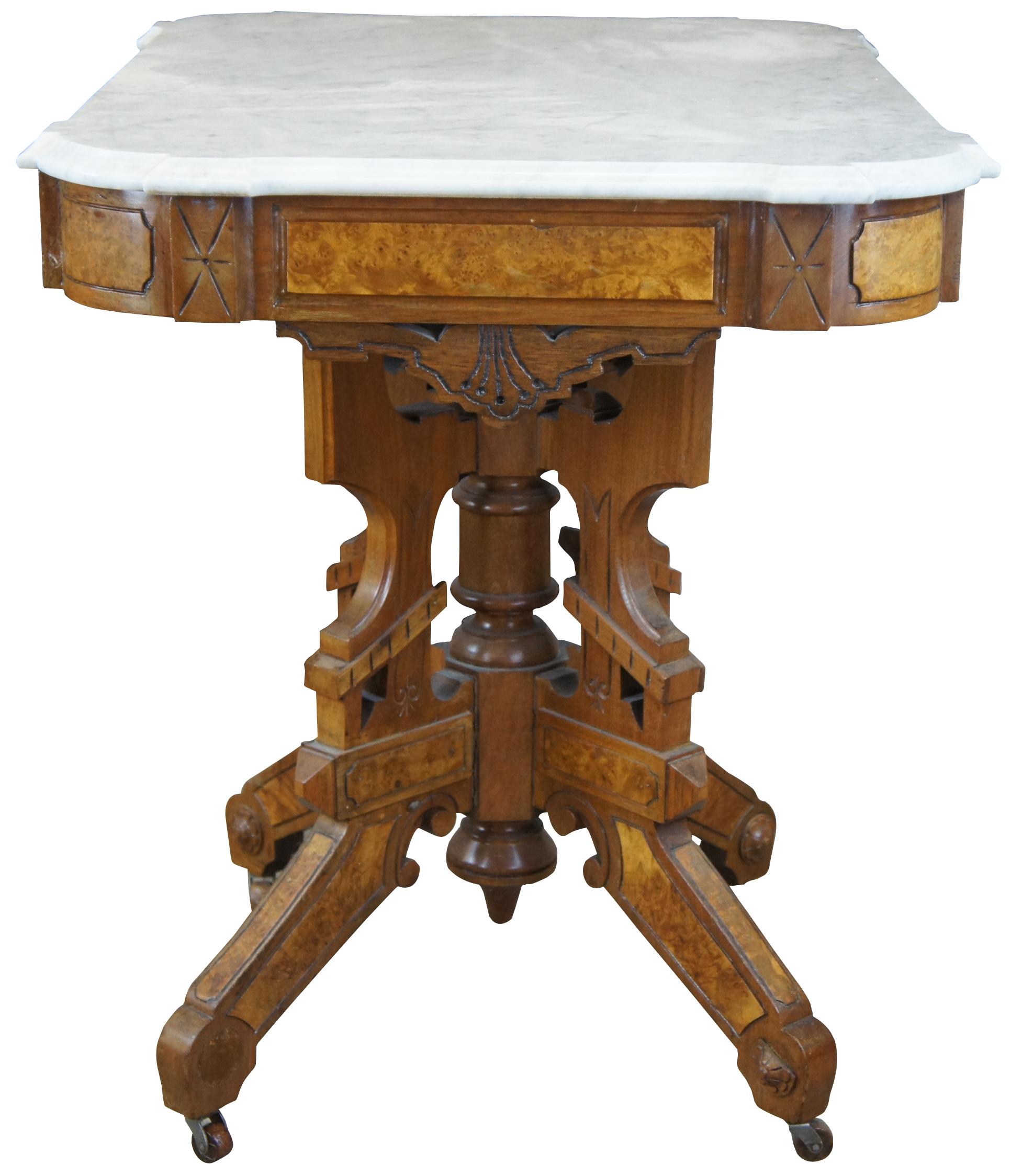 Late 19th century antique Eastlake Victorian parlor side or center table. A grande rectangular form made of walnut featuring burl accents, marble top, and a turned center support surrounded by carved panels. Measures: 34