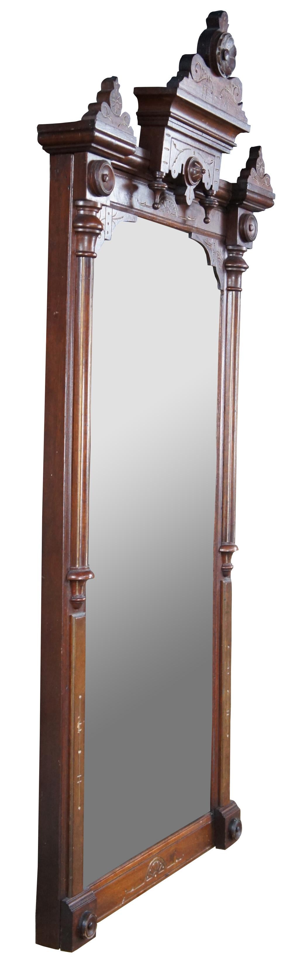 Antique Victorian Eastlake mirror. Made of walnut with burled panels. Features rectangular form with ornate crown and carvings of floral and circular medallions, drop finials and fluted columns. Measure: 67