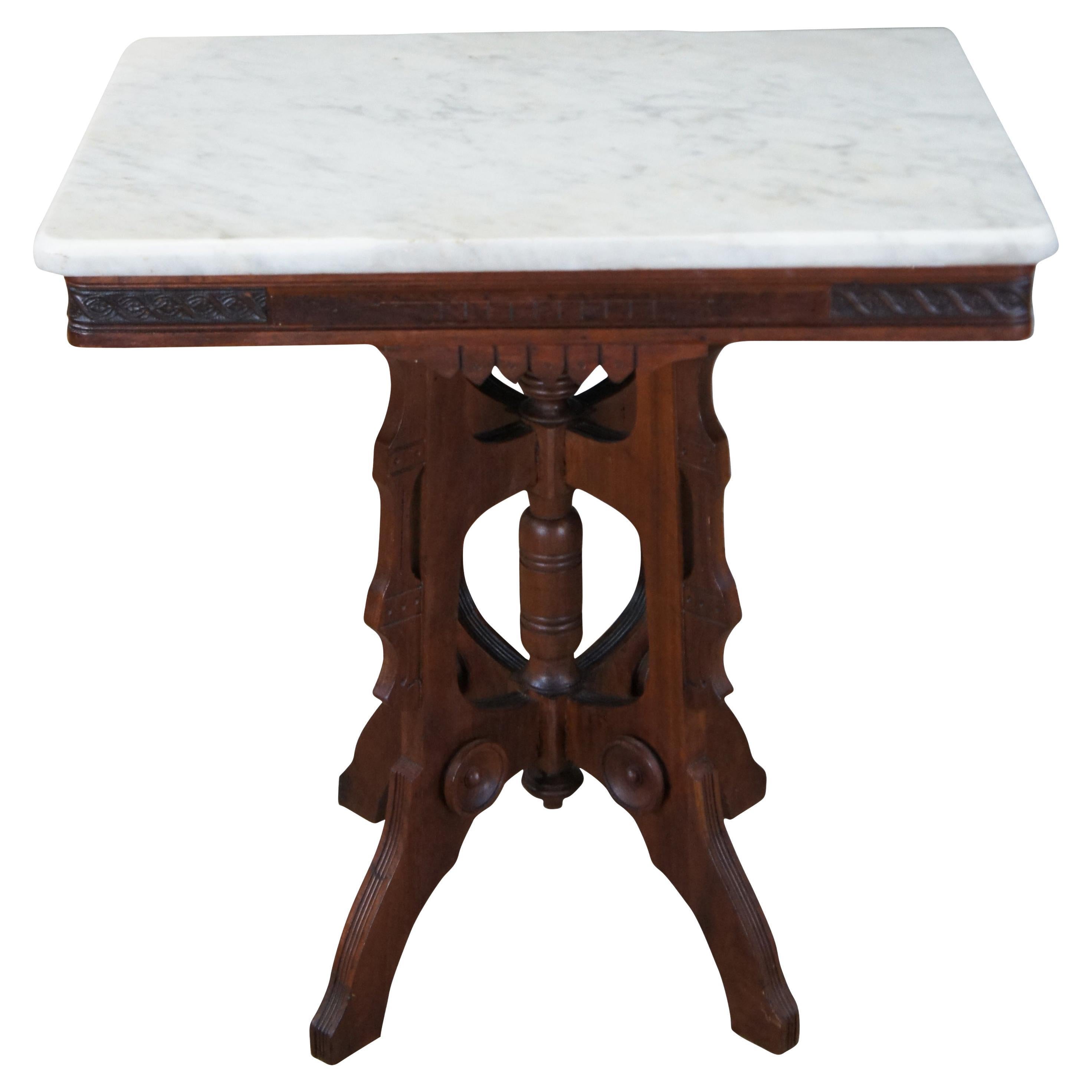 Table de salon victorienne en noyer de la fin du 19e siècle.  Whiting présente une forme rectangulaire avec un plateau en marbre blanc surmontant une frise sculptée.  La table repose sur une base ouverte avec quatre pieds et des ornements