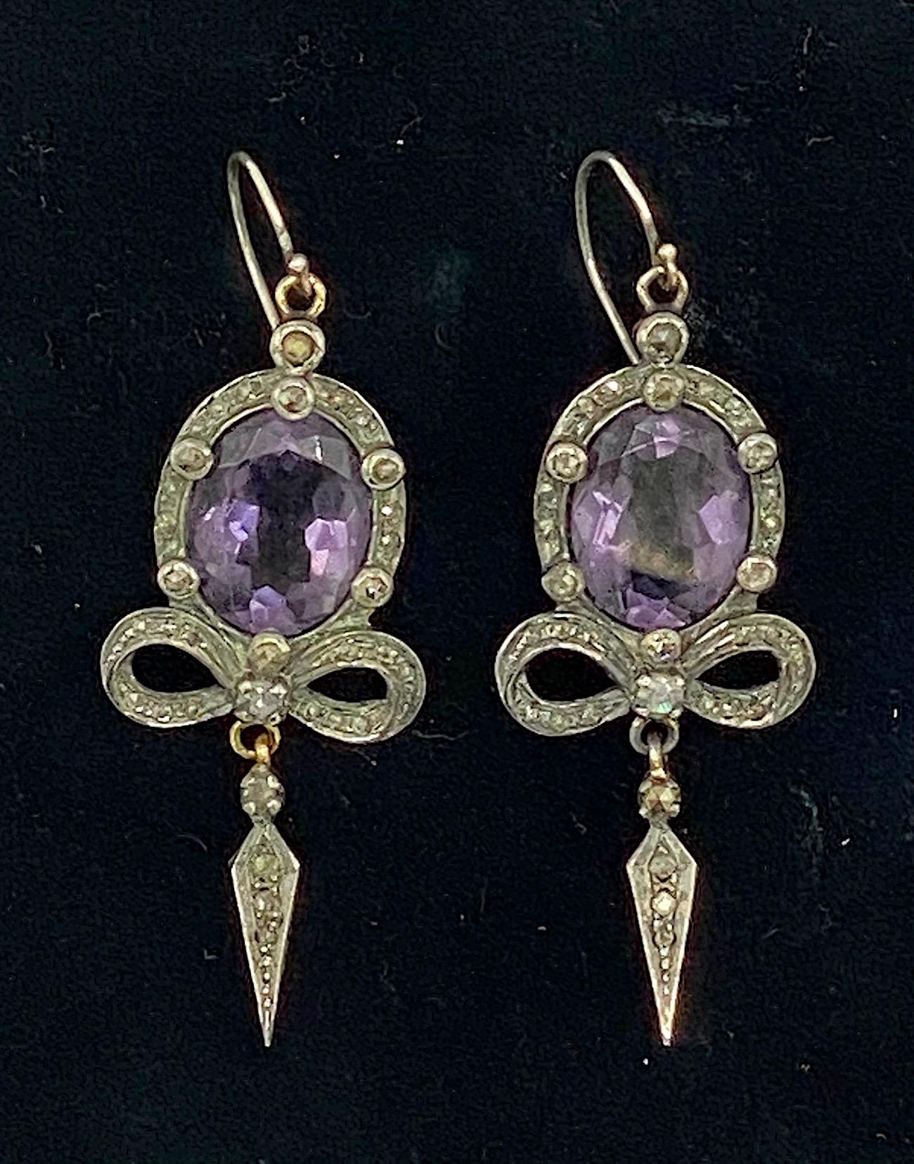 A charming pair of antique Victorian Edwardian pair of sterling silver, amethyst and diamond pendant earrings. The earrings have a French wire for pierced ears. The earrings are sterling sliver and feature a large oval amethyst stone 11.5 mm wide,