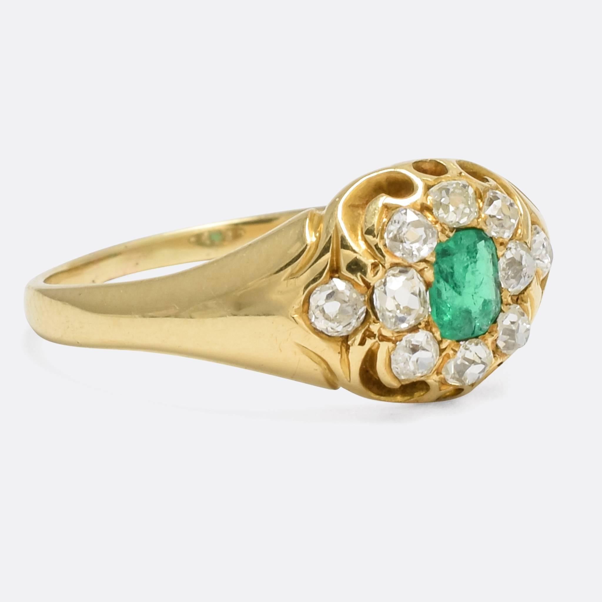 A beautiful antique cluster ring set with a vibrant emerald and ten old mine cut diamonds. The pierced gallery displays chased scroll detailing, and the ring is modelled in 15k gold throughout. A fine piece, the design is very typical of the late