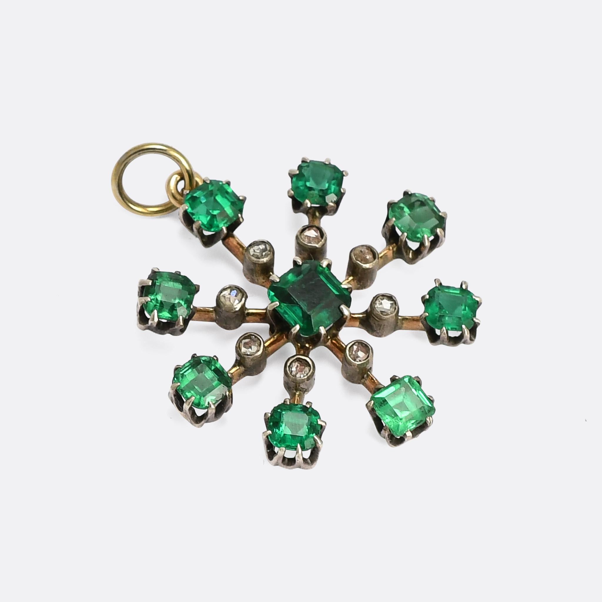 A striking antique starburst pendant dating from the late Victorian period, circa 1890. It's set with nine vibrant emerald paste gemstones and rose cut diamonds arranged on eight knife-edge lobes around a central paste. Crafted in 9 karat gold with