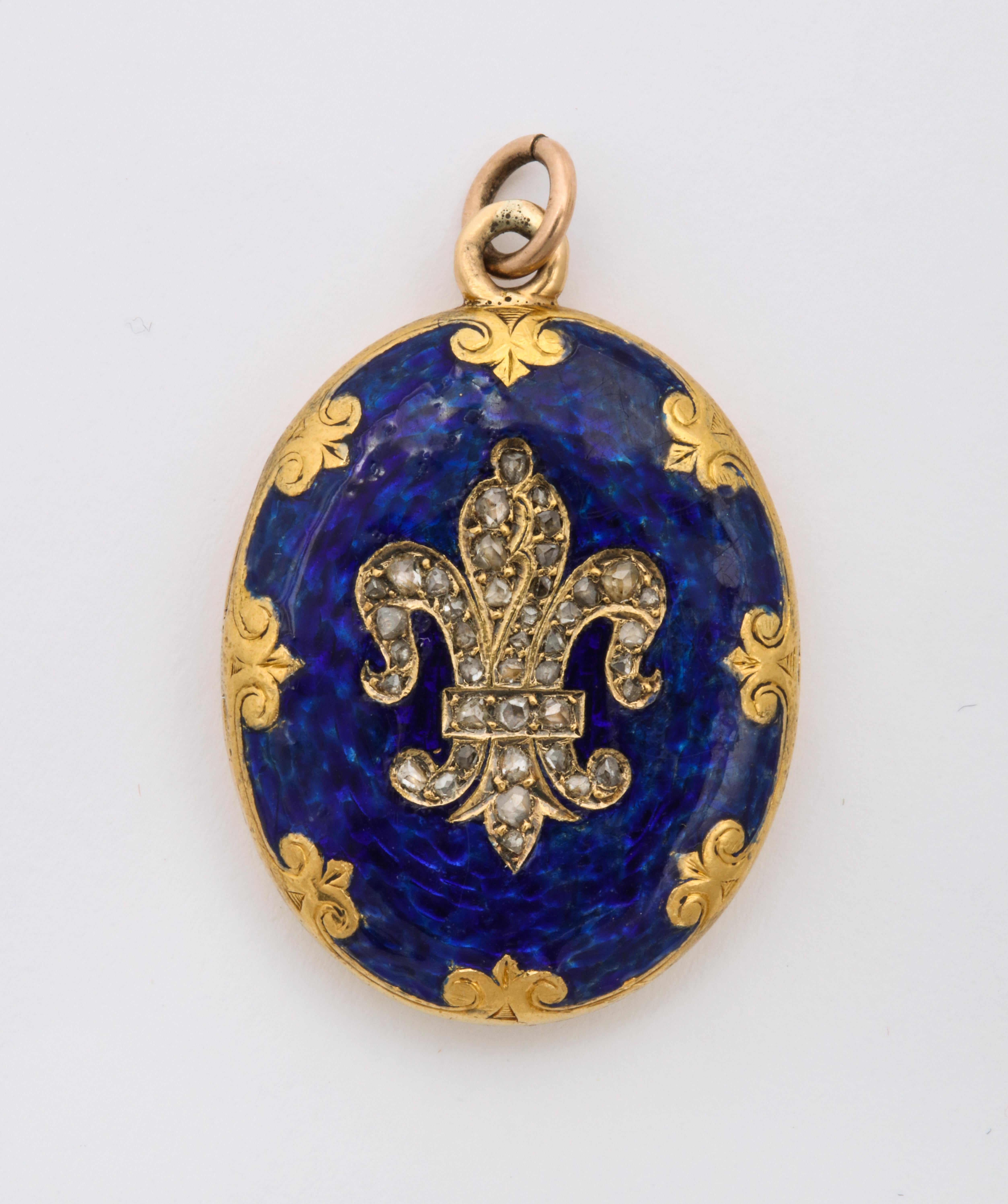 The color of delicious opaque blue enamel showcases an 18 Kt gold fleur de lis sparkling with antique cut diamonds The regal colored pendant is made more so by the rich gold crowns that define the border around the circumference. The color and