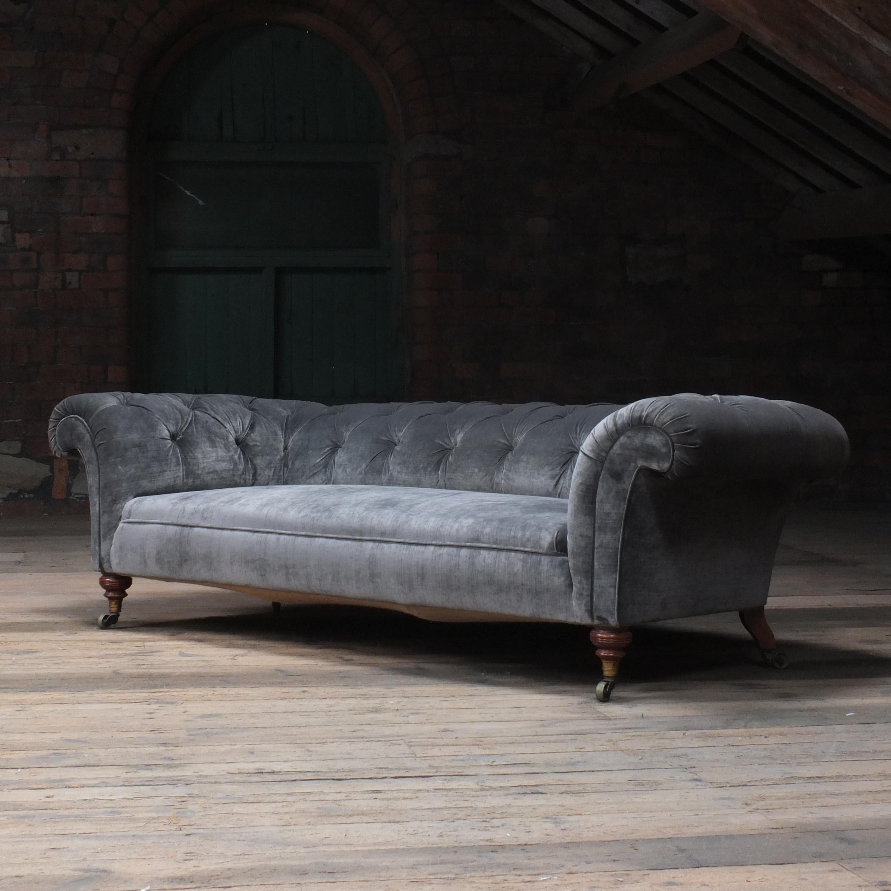 A Large country house English chesterfield sofa by Howard & sons - London. Raised on Howard's uniquely ring turned walnut legs to the front and out swept to the back, all on Howard & son's stamped castors. The low sleek design of Howard