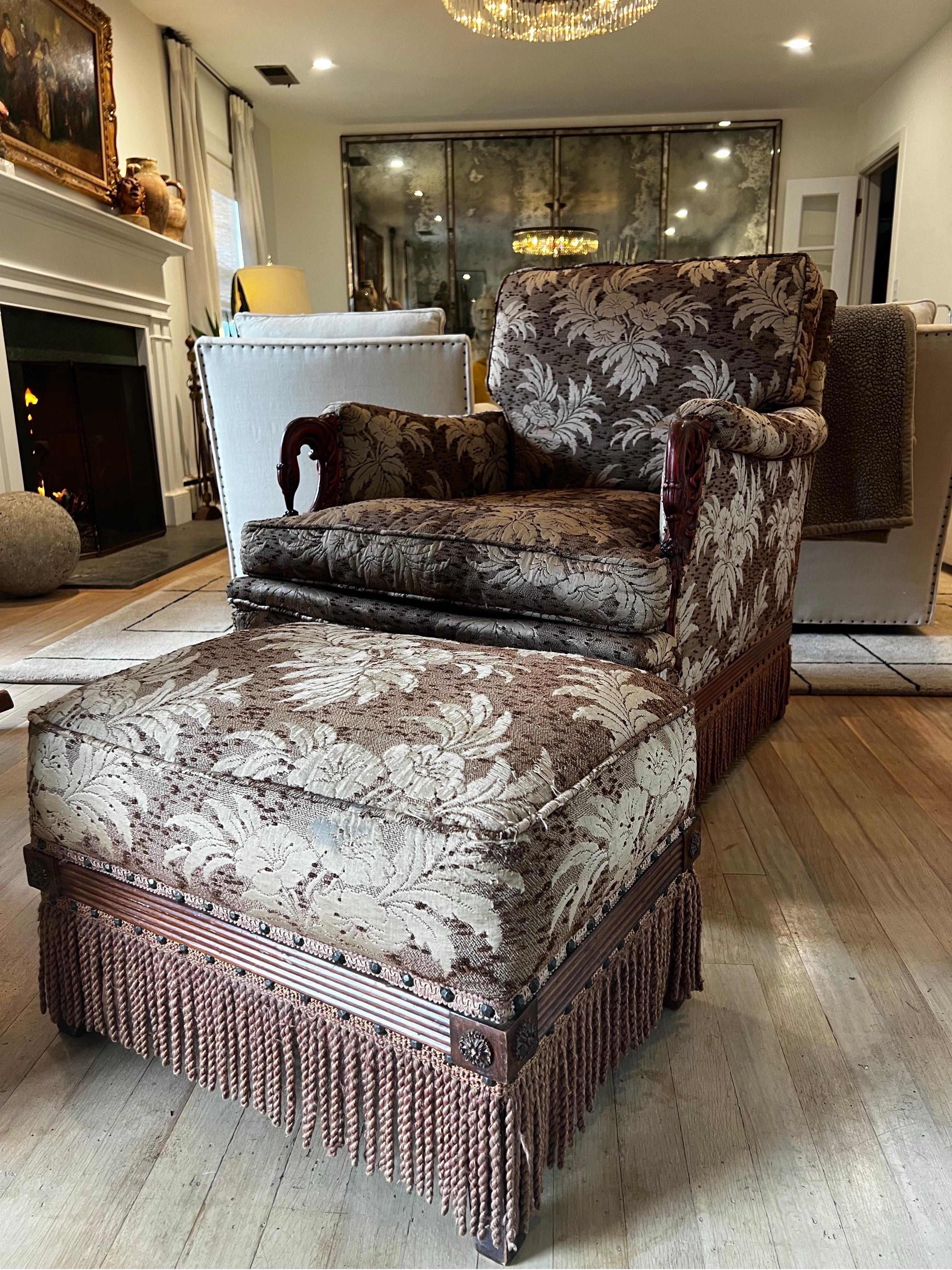 Impressive custom Victorian armchair with ottoman.  Built for comfort and crafted in mahogany with carved arms and trim along the base.  Upholstered in Pennsylvania with floral japanese esq fabric with creamy greenish silver tone.  Skirted with