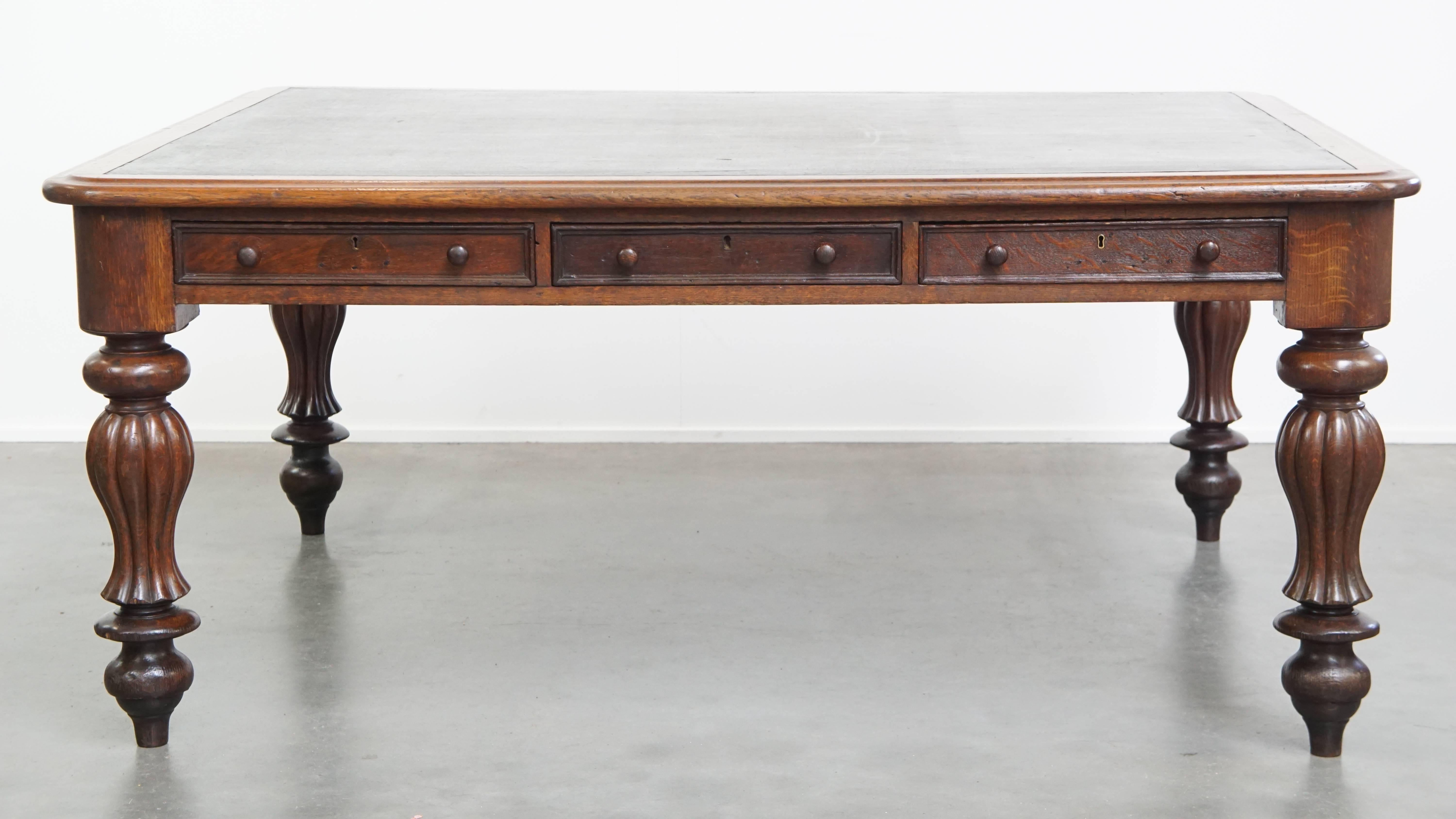 Offered here is this large, unique, and antique Victorian English oak writing desk / library table / partner desk with a leather top. This exceptional library table is a stunning and luxurious addition to almost any space—whether in your home or at