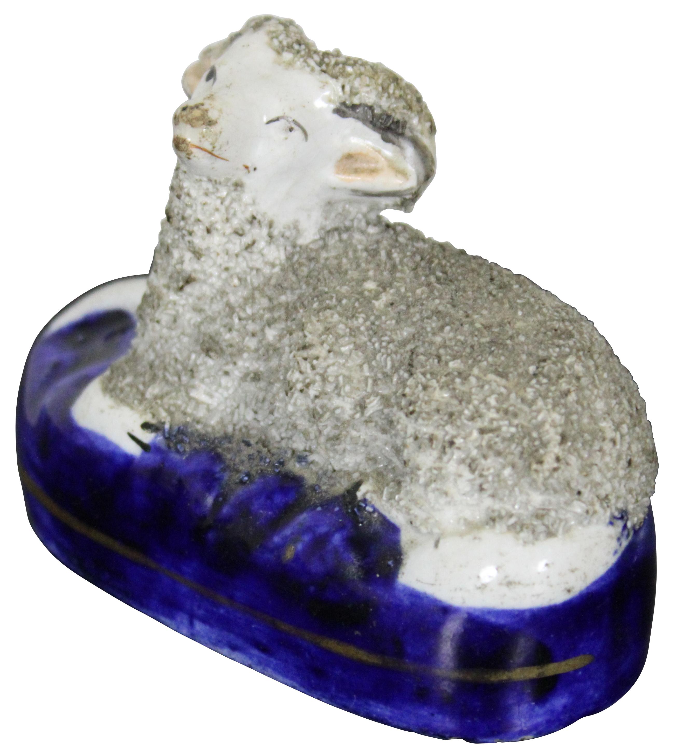 Antique Staffordshire figurine of a confetti porcelain ram laying on a blue base.
