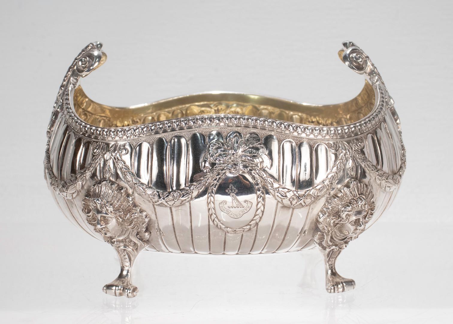 A fine Victorian crested English bowl.

In sterling silver.

By George Aldwinckle. 

In a George II Revivalist style with scrolled feet and legs that terminate in human faces supporting a ribbed body with a scalloped rim decorated with a laurel leaf