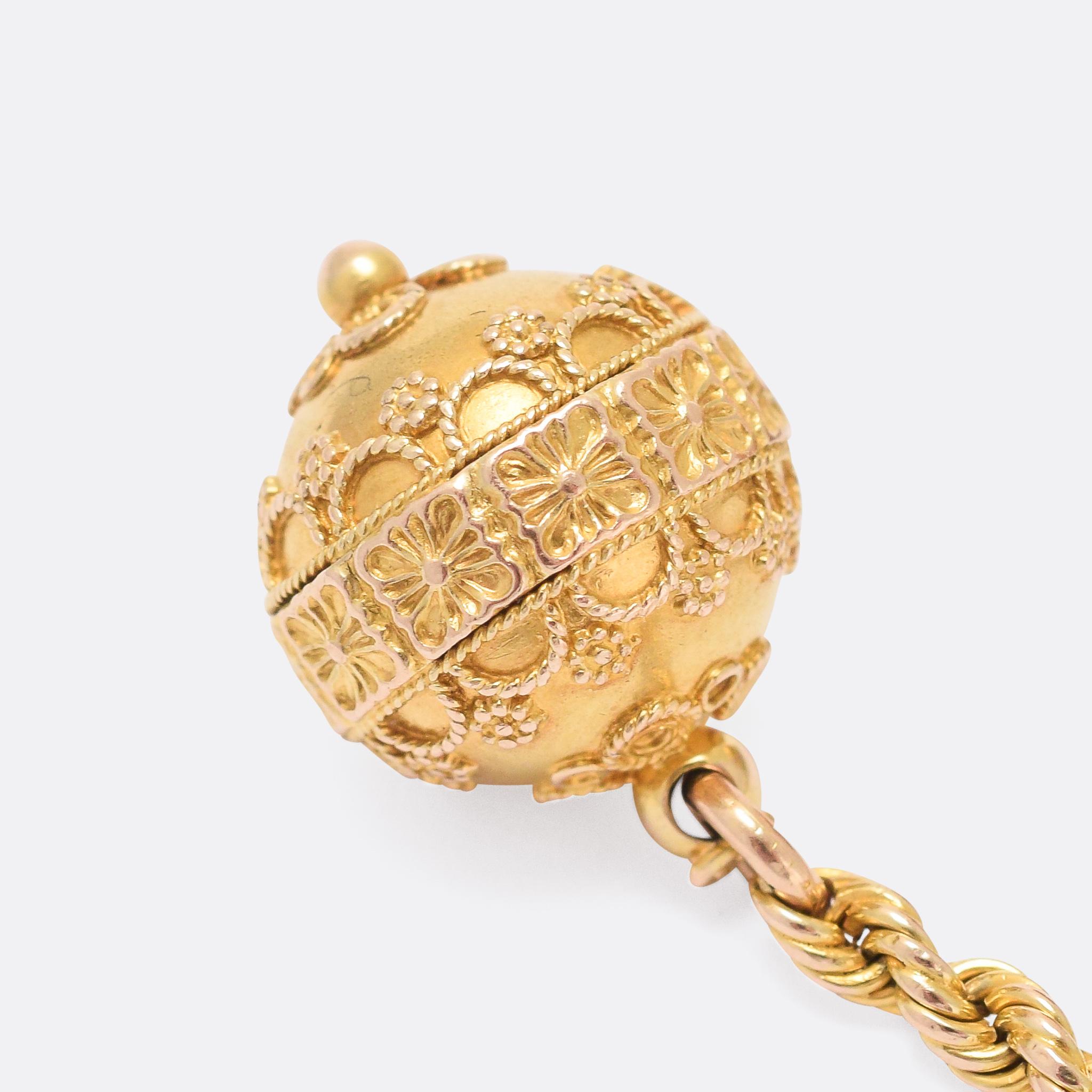 A cool antique watch fob featuring two golden orbs decorated in the Etruscan Revival style and dangling on rope-twist chains from a swivel clasp. Modelled in 15 karat gold throughout, the orbs have applied gold ropework and granulation motifs. There