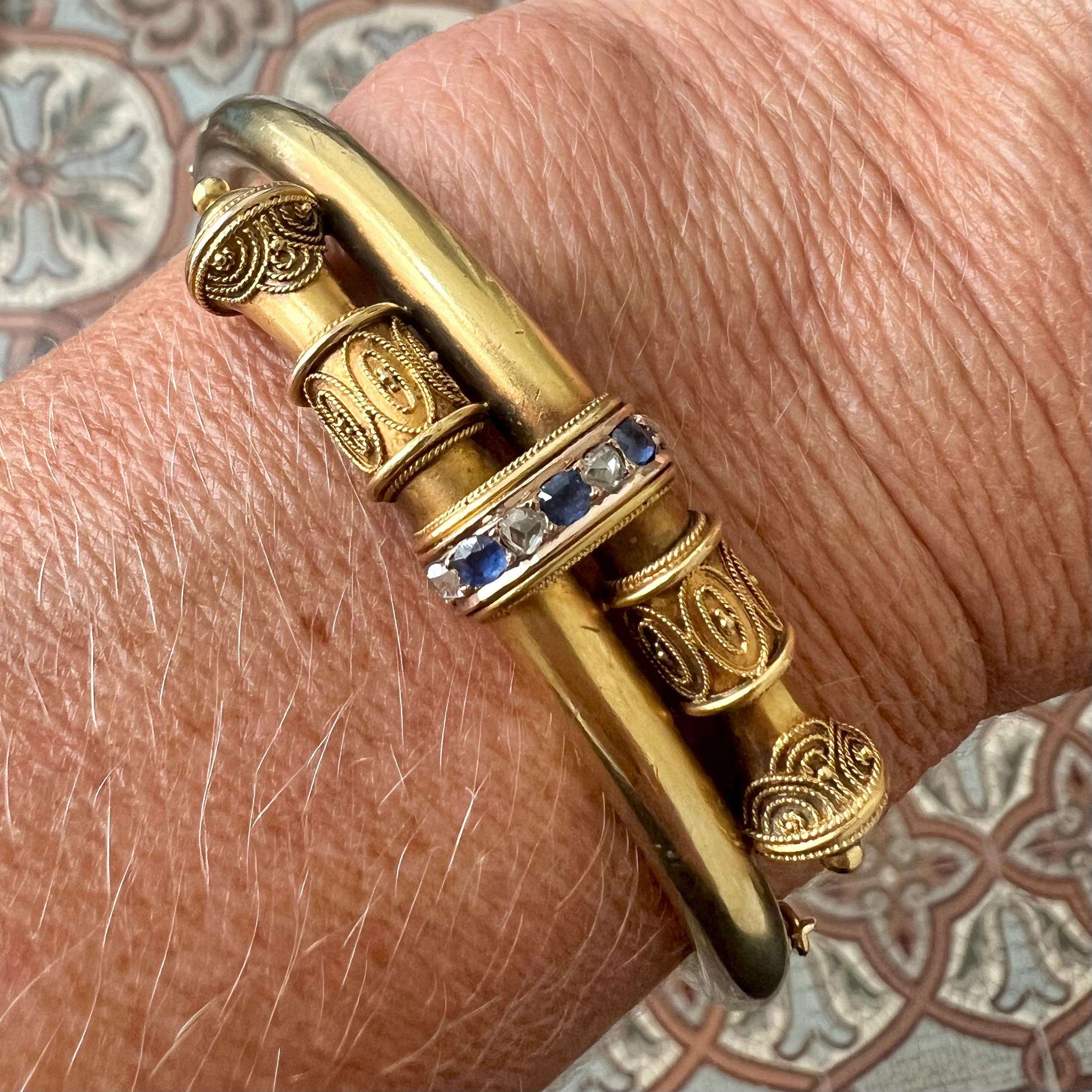 Un bracelet antique raffiné en or jaune 14 carats, datant d'environ 1880, et un beau témoignage du style néo-étrusque de l'ère victorienne.

La partie centrale présente une délicate ligne de trois saphirs bleus facettés alternant avec quatre