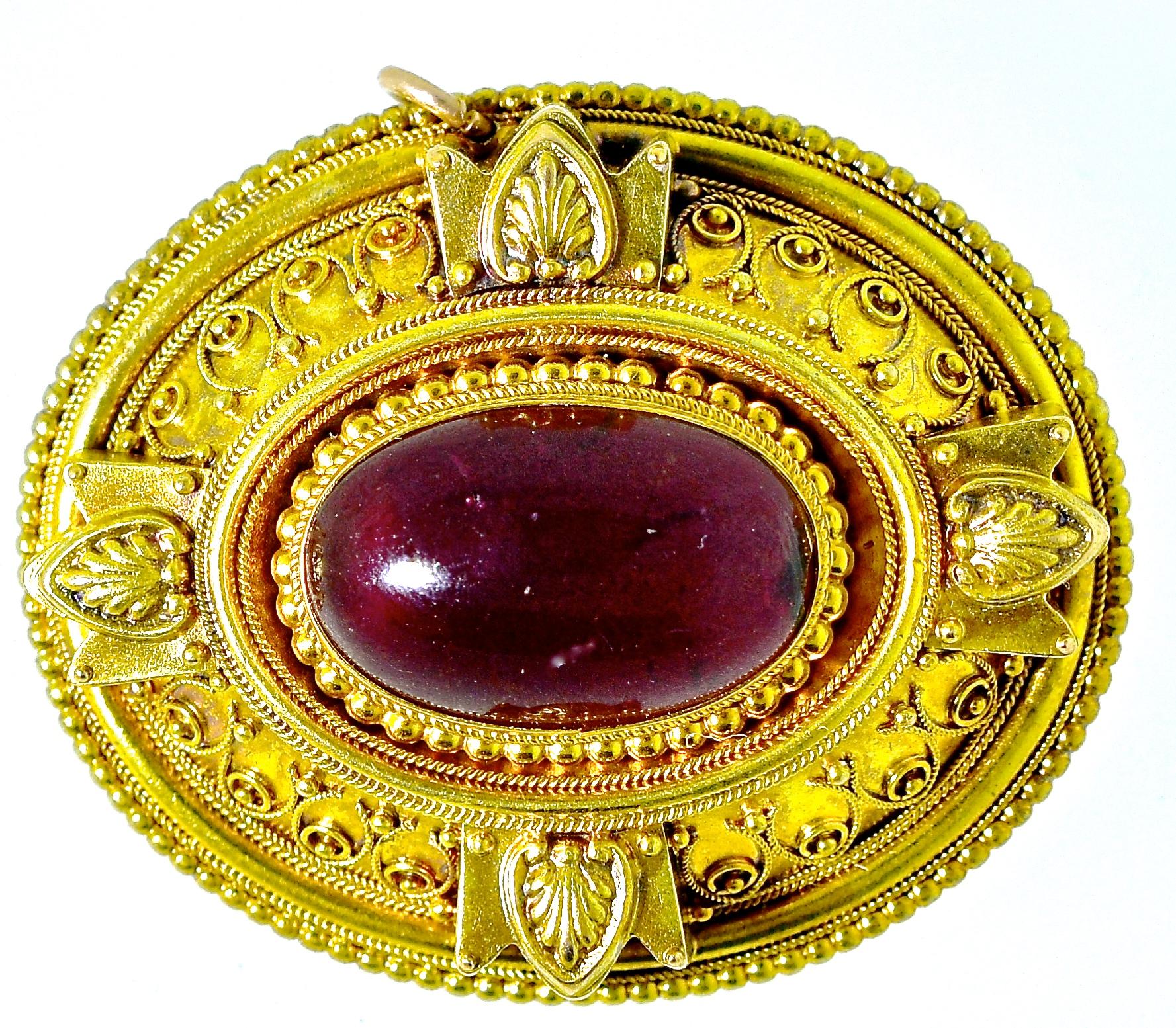 Antique, from the last quarter of the Nineteenth Century, large gold brooch centering a carbuncle natural garnet weighing approximately 9 cts., and surrounded by fine bead and wire work, Etruscan Revival.  On the verso, is the original hair receiver