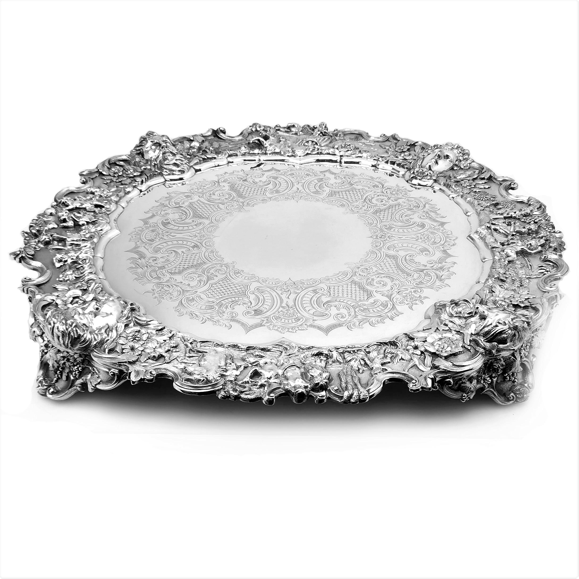 An impressive antique Victorian Silver Plated Salver. This ornate Salver is of extremely large size and very heavy weight. The Salver has a beautiful decorative border with four faces above the four feet of the salver. The borders between the faces