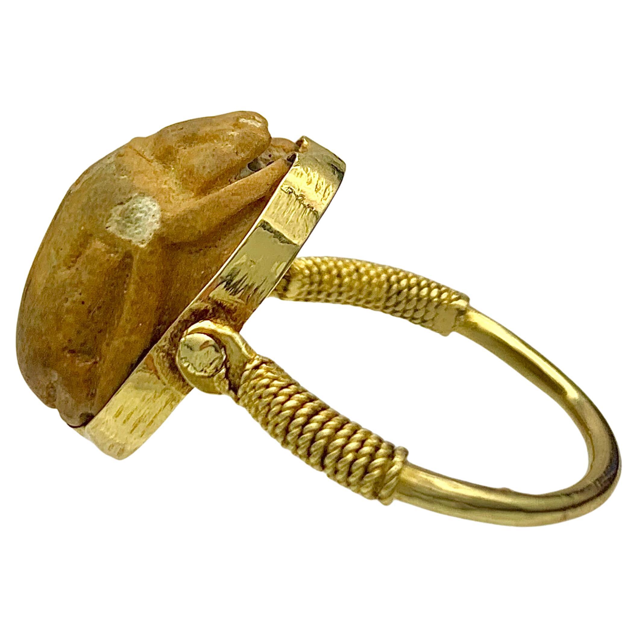 Dieser antike Fayence-Skarabäus ist in einen drehbaren Ring aus 18 Karat Gold gefasst.  Die Ringschultern sind mit gedrehtem Golddraht verziert. Im alten Ägypten sollte der Skarabäus den reibungslosen Übergang von einem Leben zum anderen