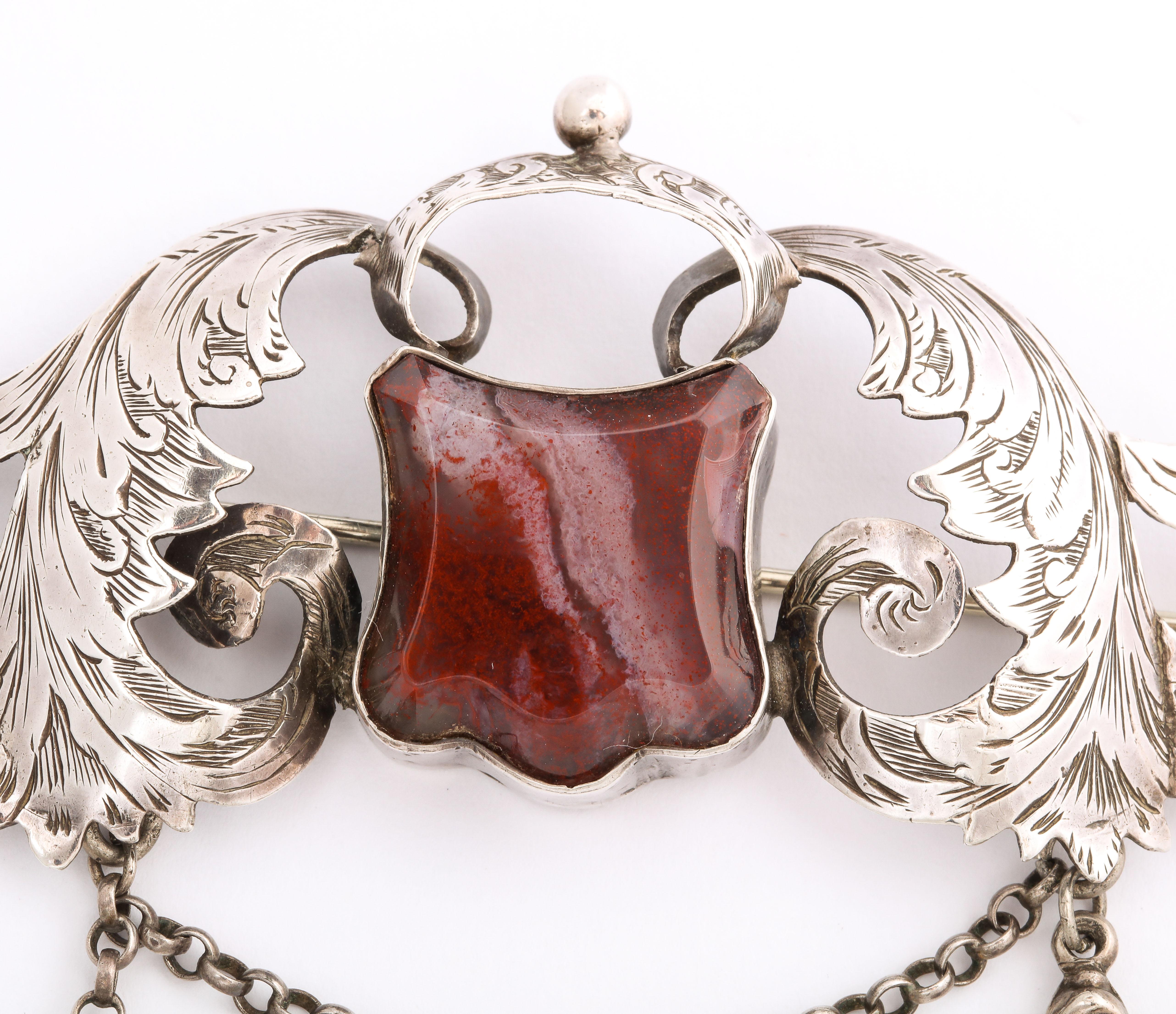 I have not seen another work of art like this large Hilliard and Thomason scrolling, agate crested Scottish brooch. It is a rare  brooch made by these well known silversmiths with their telltale link and drop chain and slide clasp. The brooch