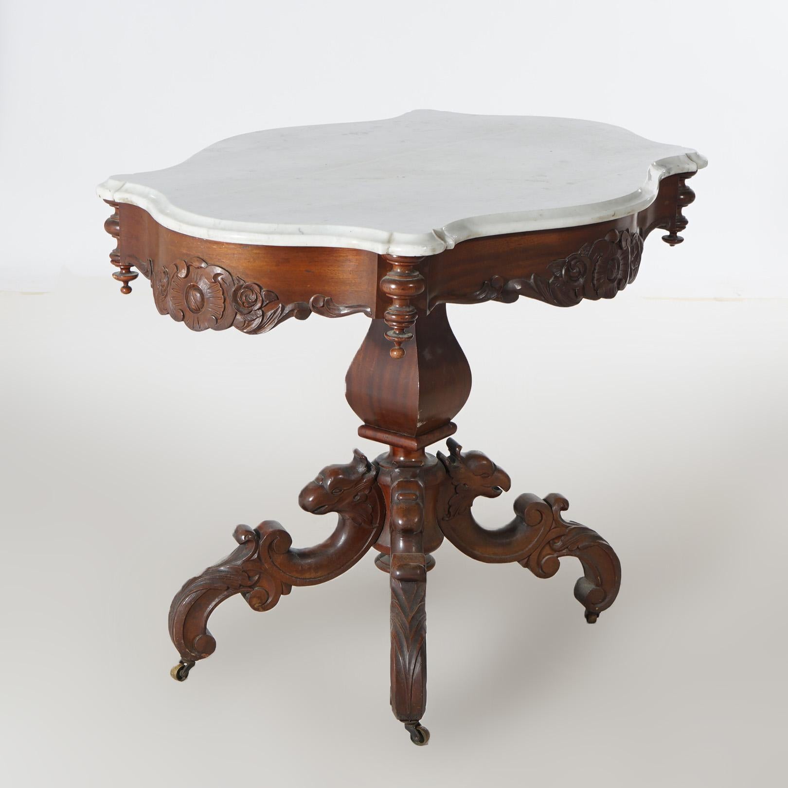 An antique Victorian parlor table offers beveled and shaped marble top over carved walnut base having floral decorated skirt and raised on griffin form scroll legs, c1880

Measures- 30.75''H x 38.25''W x 27''D