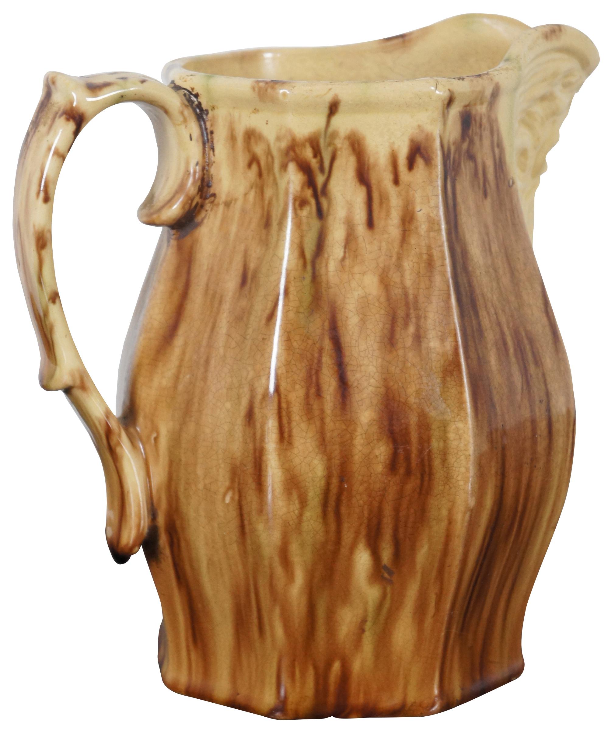 Antique Victorian majolica style pitcher with faceted sides, the face of a man with a beard under the spout and glazed coloring reminiscent of wood grain.
 
