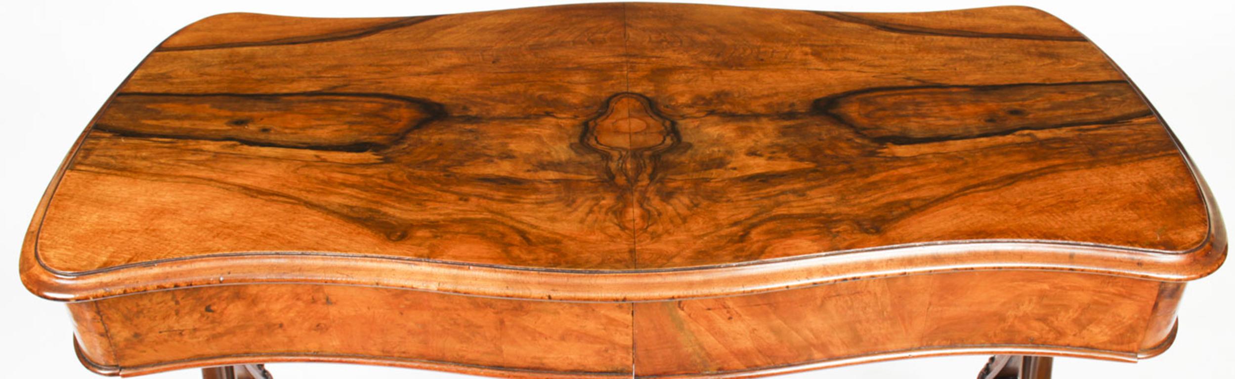This is an elegant antique Victorian figured walnut writing table, also perfect as a sofa table, Circa 1870 in date.

The shaped top is above two frieze drawers and it is raised on elegant turned and carved supports united by a turned and carved