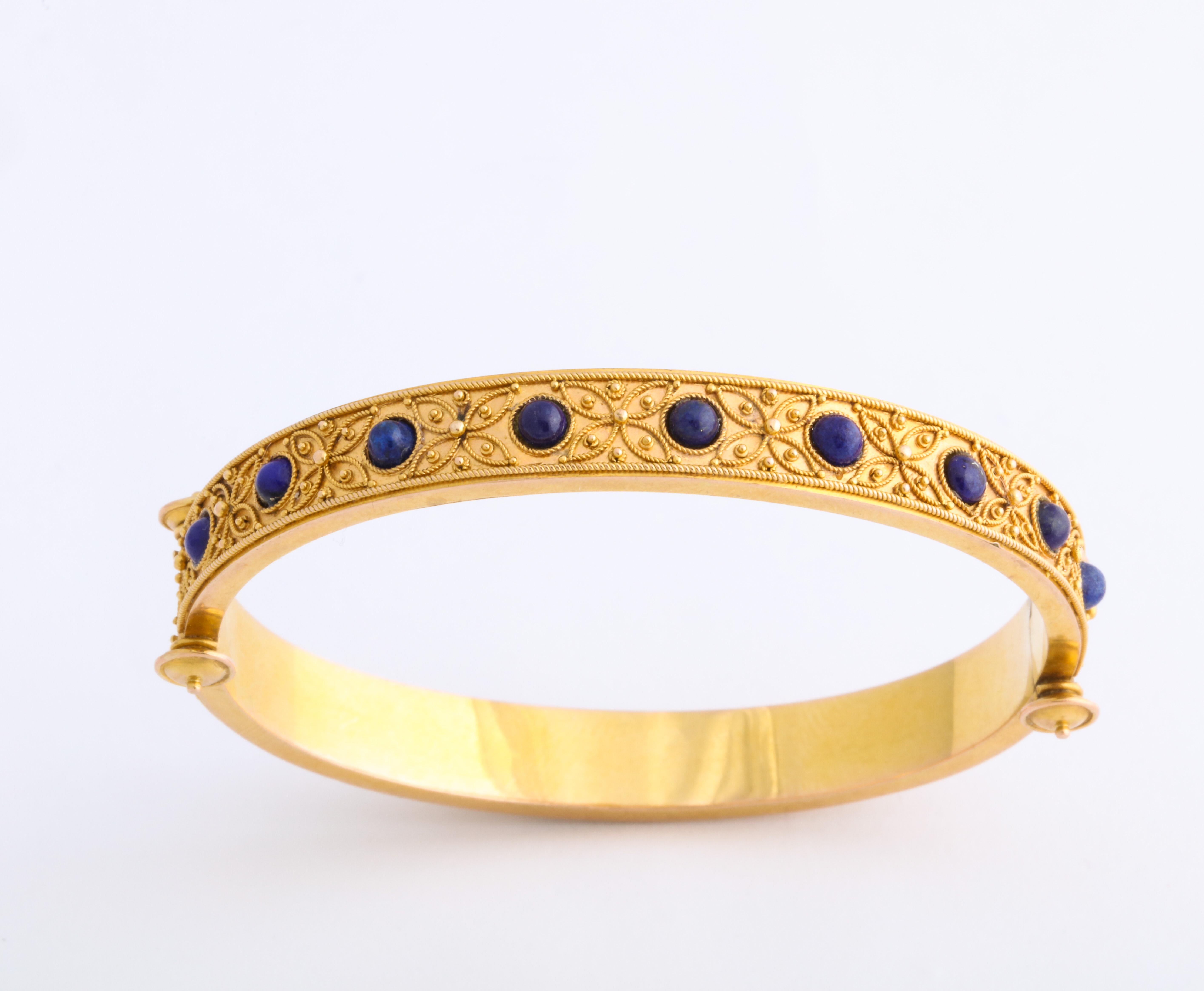 Top of the line in quality, the 18 Kt Etruscan Revival bracelet is set with cabochon lapis lazuli stone from east to west on its face interspersed with very fine wirework forming pointed petal flowers and highlighted with tiny granulation all