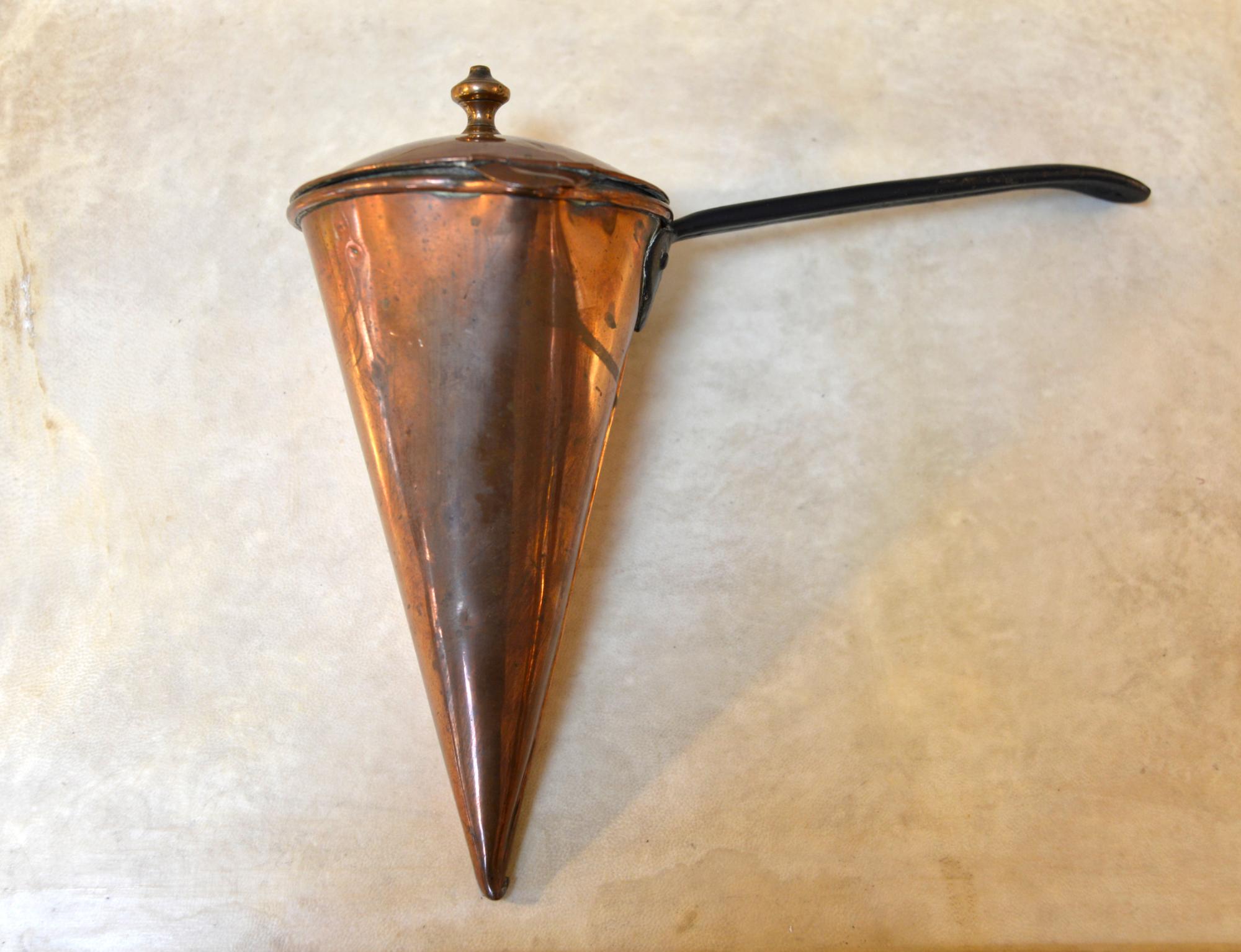 This unusual antique in a conical form, is actually an ale warmer / cider muller with a lid and side spout, a rolled copper seam and Cast iron handle. The simple cone would be stuck point-down into the heat from the top of the fire and were