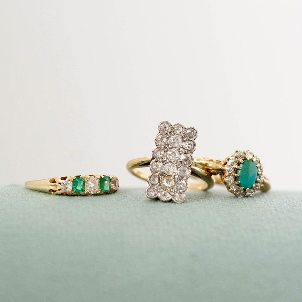 Our antique Victorian five stone ring, features a stunning trio of antique diamonds, flanked by a pair of bright green emeralds, all set in a luxurious 18ct gold band. The exquisite design is a testament to the skilled craftsmanship and refined