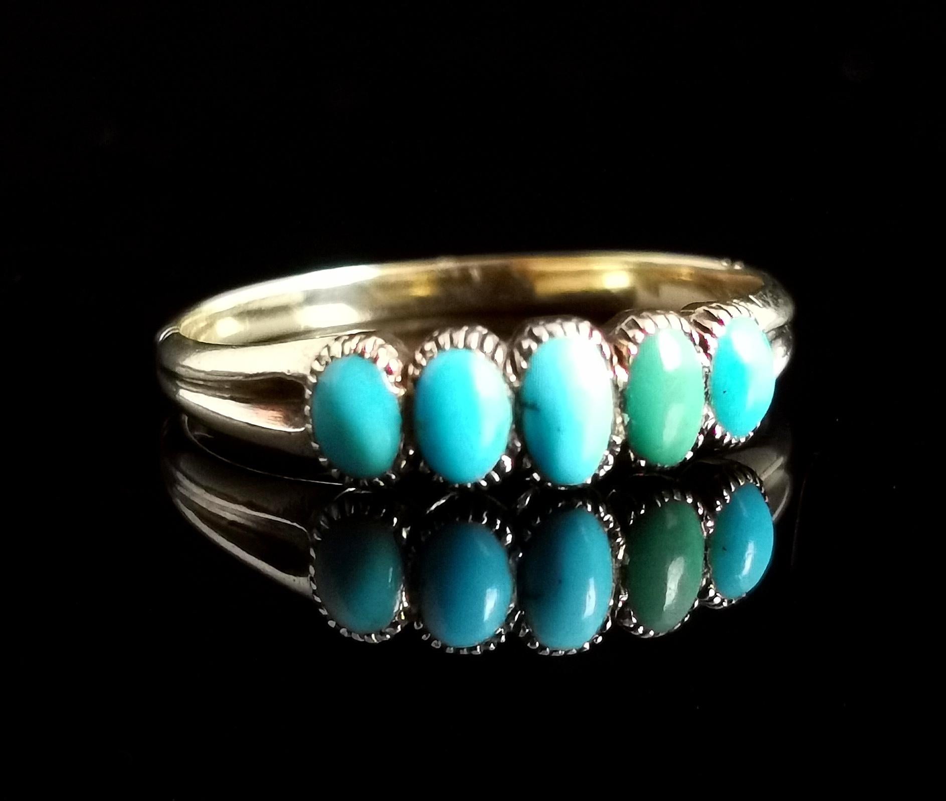 A pretty antique, early Victorian era turquoise five stone ring.

The face of the ring features five beautiful turquoise in an array of greens, graduating smaller from the largest centre stone.

It has decorative shoulders leading on to a slender