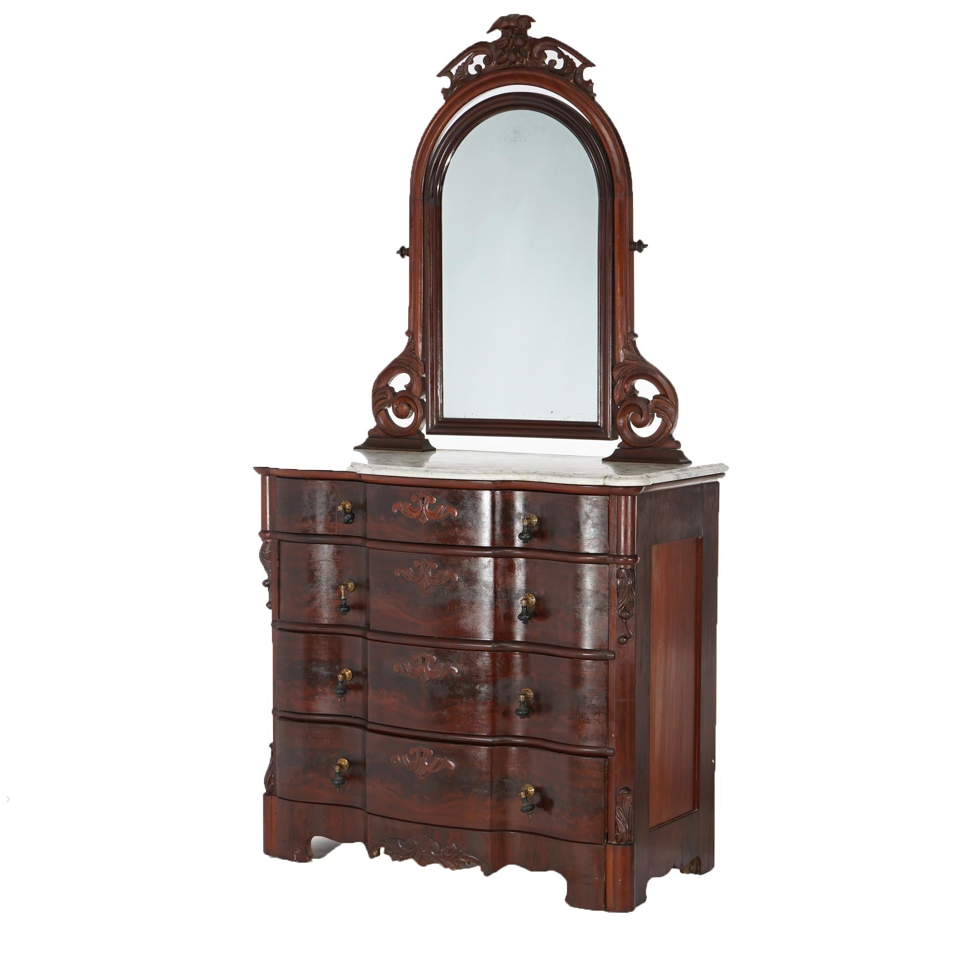 An antique Victorian dresser offers flame mahogany construction in swell front form with beveled marble top over four long drawers with flanking carved elements; mirror with carved mahogany frame having scroll form crest with fruit and nut elements,