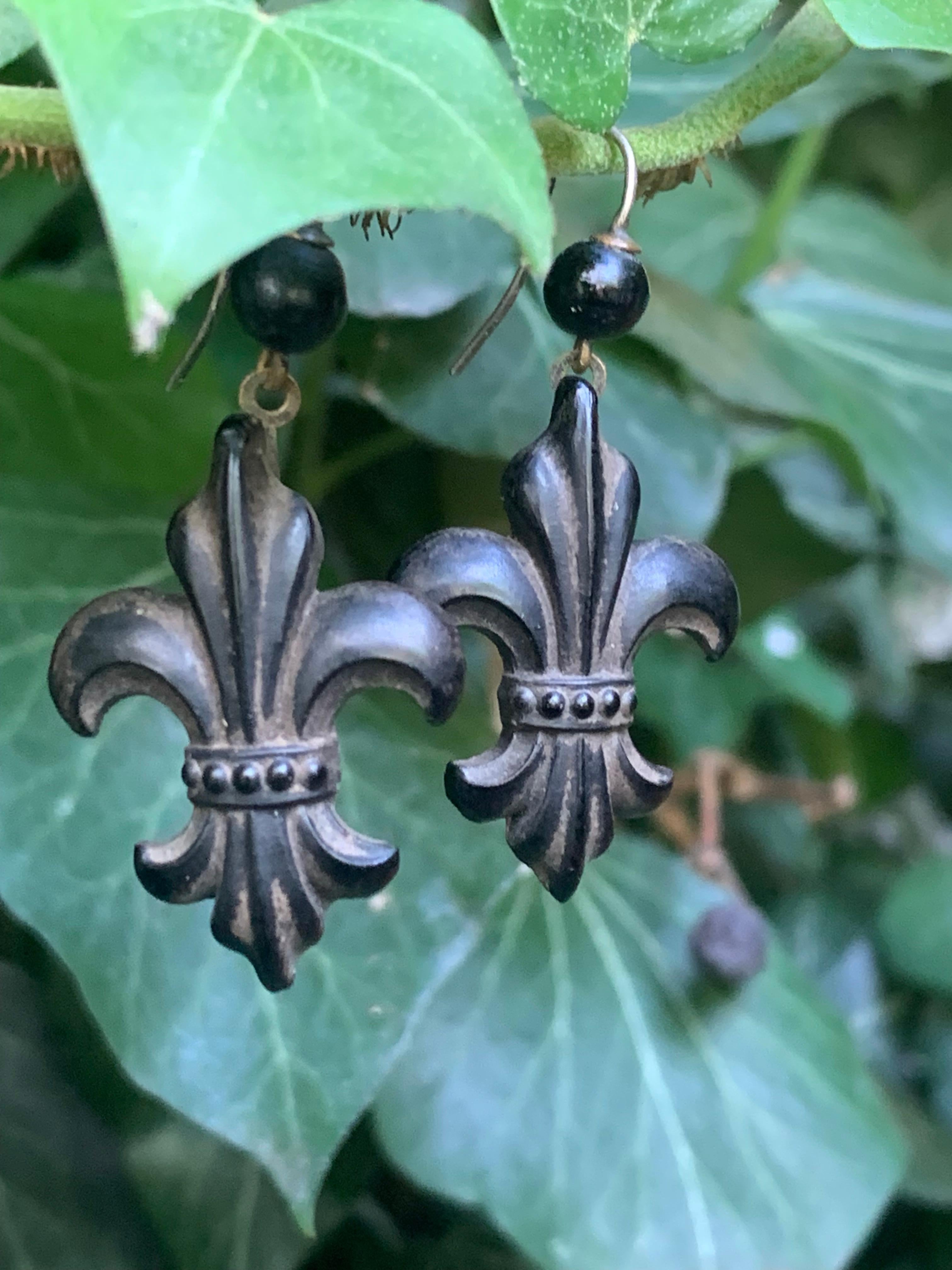 This rare pair of dangle Fleur-de-Lys earrings was created in 1880 ca. The fleur-de-lys are made out of  moulded vulcanite, a material made from rubber or kautschuk patented by Goodyear in 1864. 
The earrings come in their original condition. With