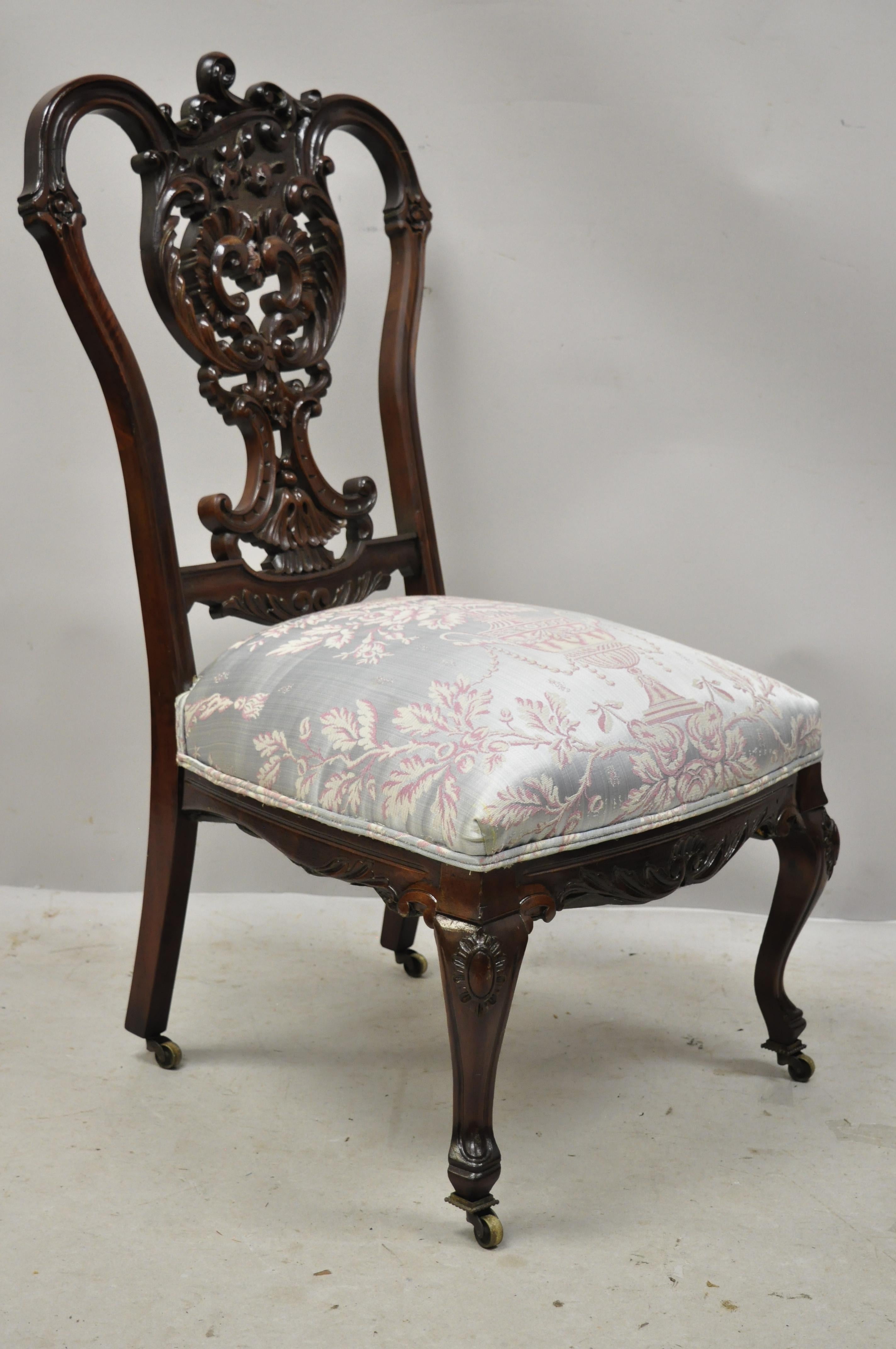 Antique Victorian Floral Scrollwork carved mahogany parlor accent slipper chair. Item features floral scrollwork carved frame, brass rolling casters, very nice antique item. Frame looks to have been refinished at some point over the years, circa