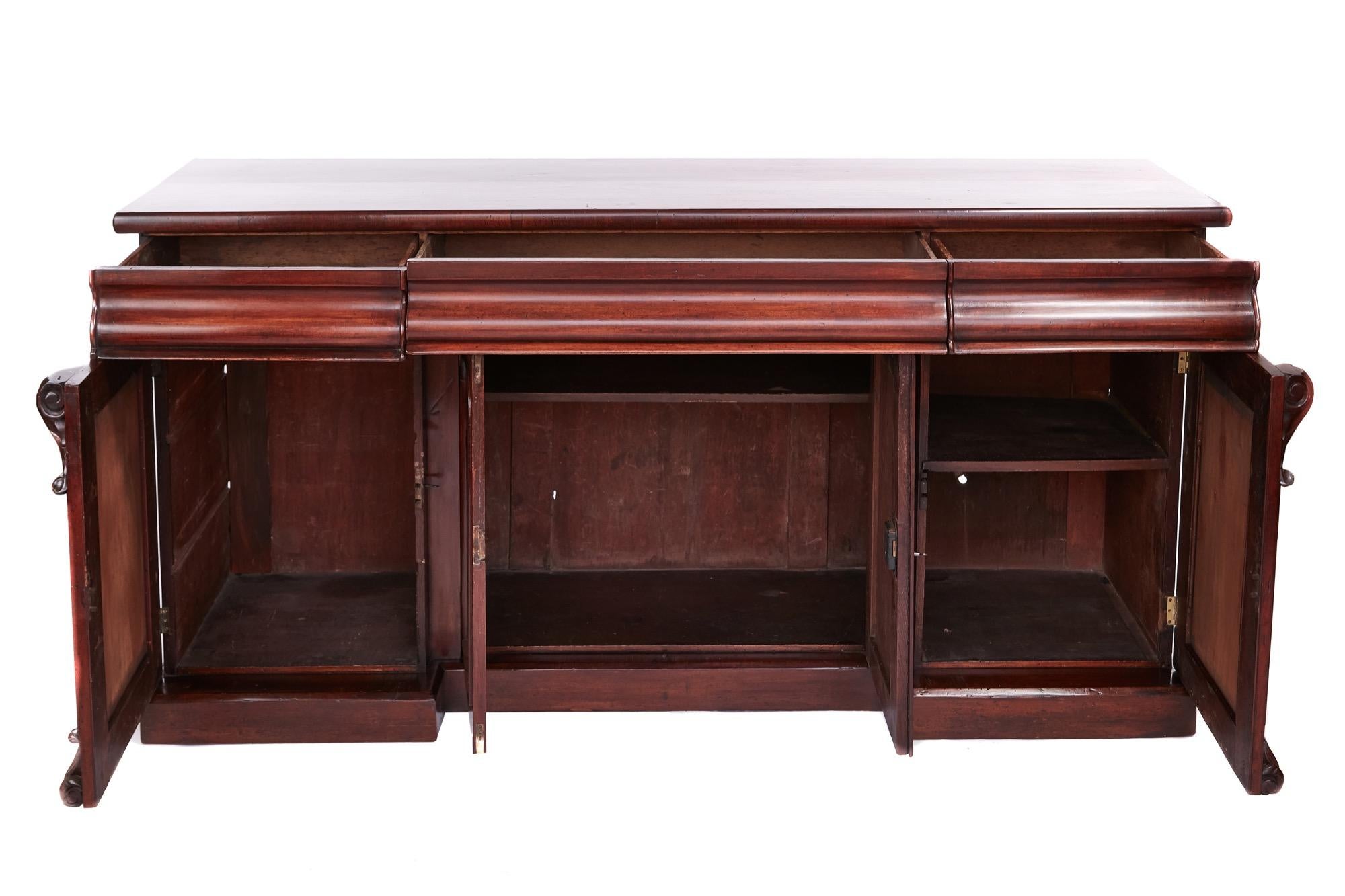 Antique Victorian four-door mahogany sideboard having a quality mahogany top with three frieze drawers and four figured mahogany paneled doors, the outer doors with carvings to the top and bottom which open to reveal a fitted interior, the sideboard