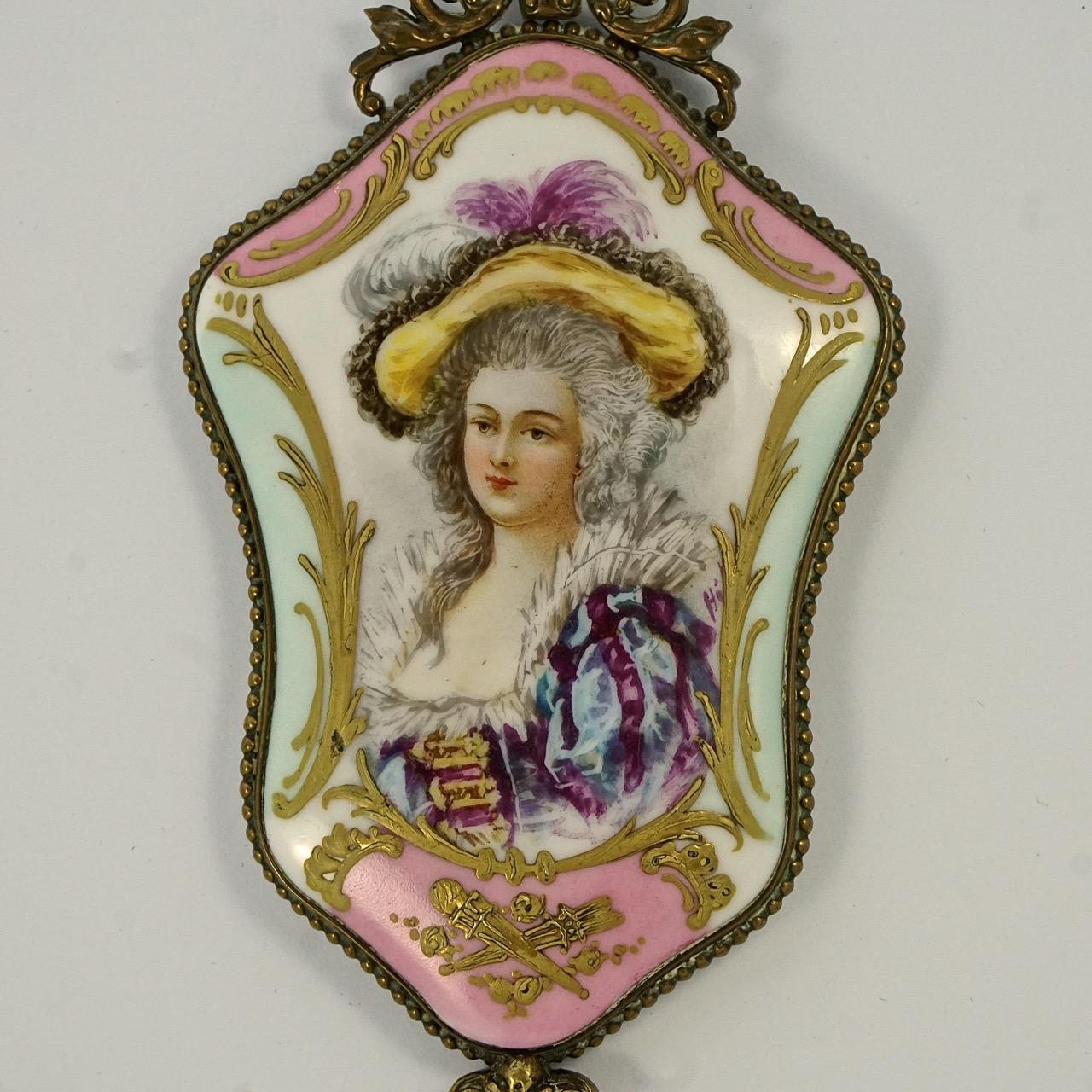 Wonderful antique Victorian French bevelled edge decorative hand mirror with a gilt finish. Featuring a painted porcelain back with a lady design and a pink and blue edging with raised hand painted gold detail. The mirror is edged with a beaded