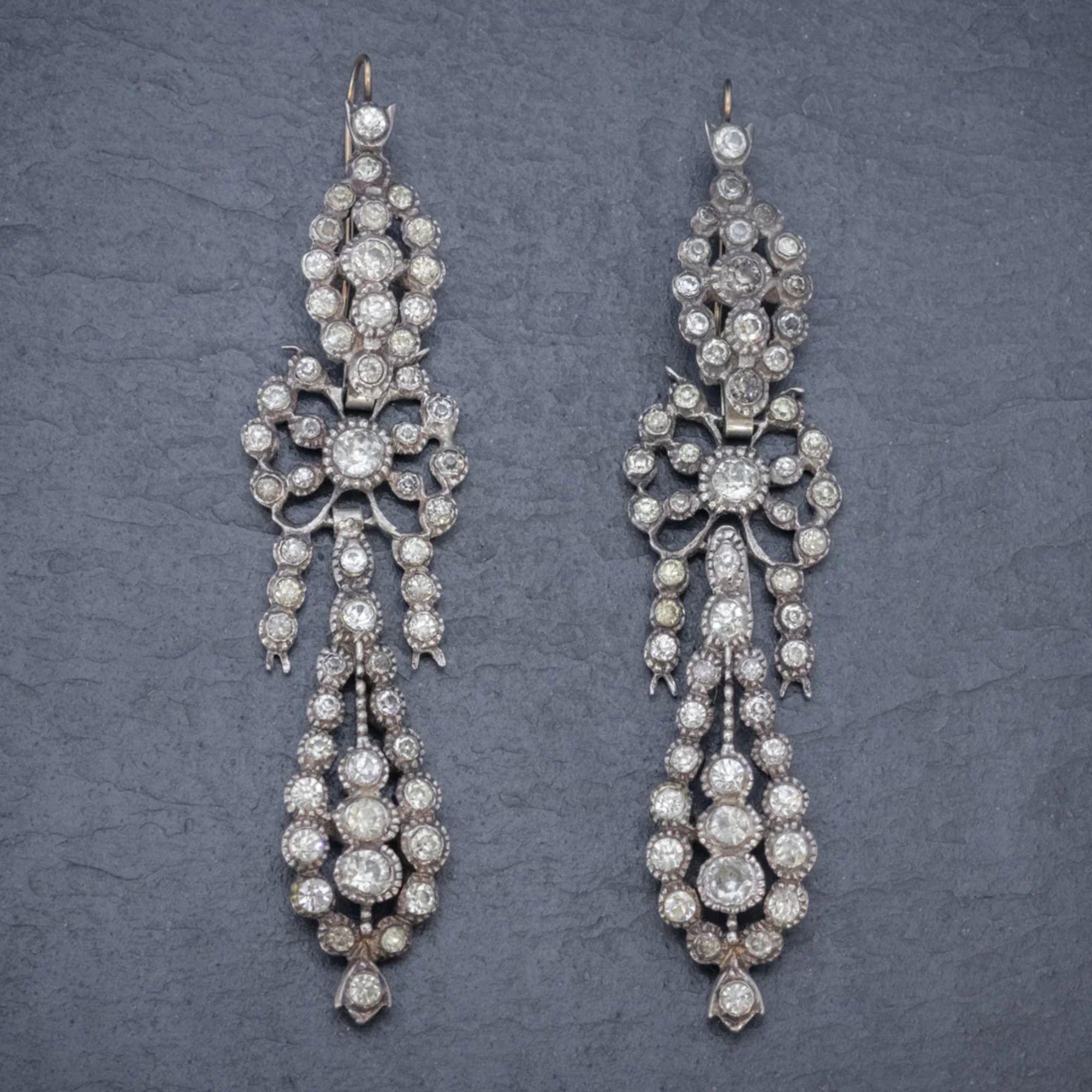 A spectacular pair of antique drop earrings made in France in the late 19th Century. Each earring is made up of three ornate sections decorated with an array of sparkling paste stones that simulate the beauty of diamonds.

Both are fashioned in