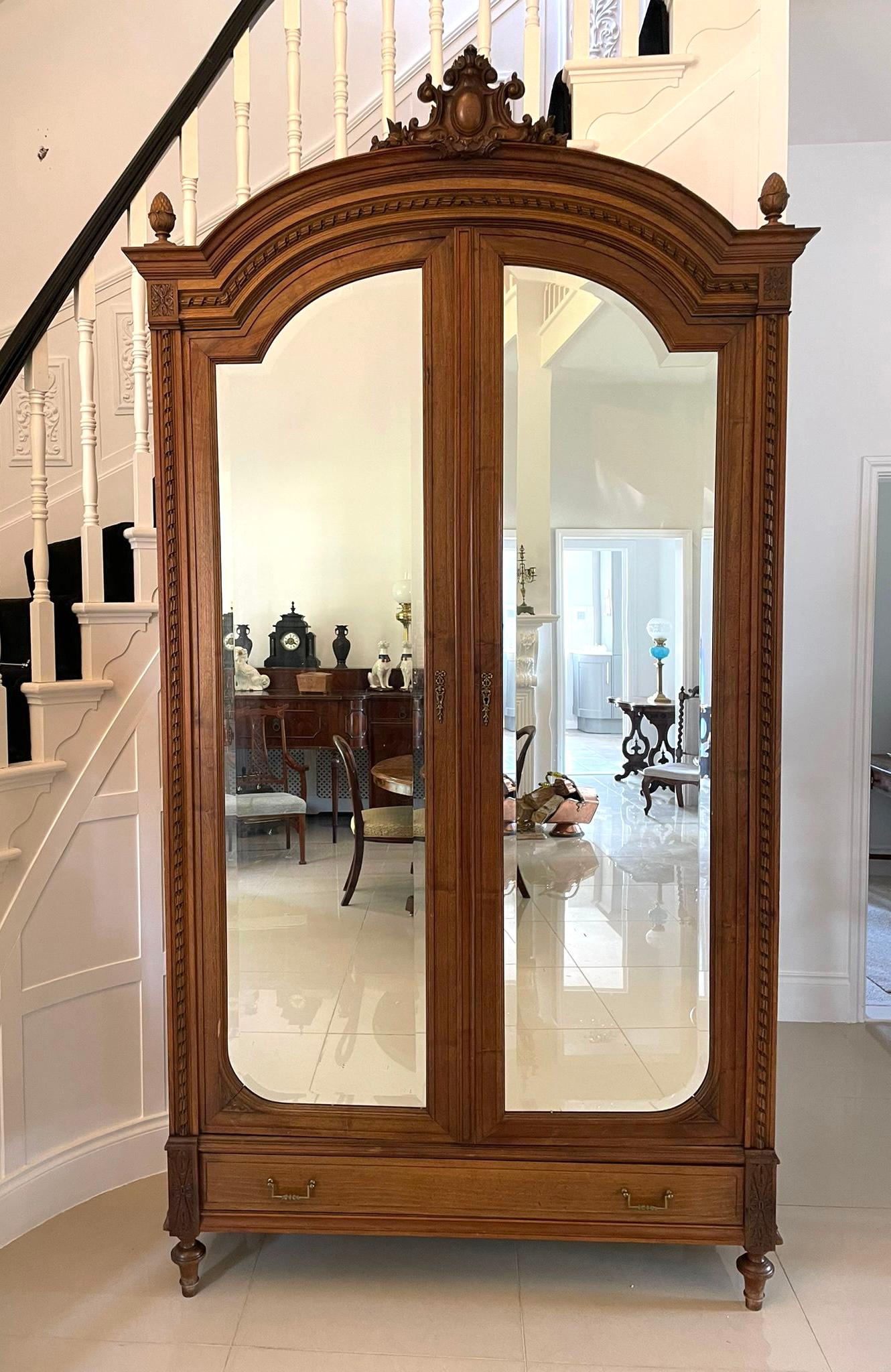 Antique Victorian French quality carved walnut wardrobe having an outstanding quality carved cornice with original carved finials above a pair of walnut framed doors with original shaped bevelled edge mirrors opening to reveal an adjustable shelved