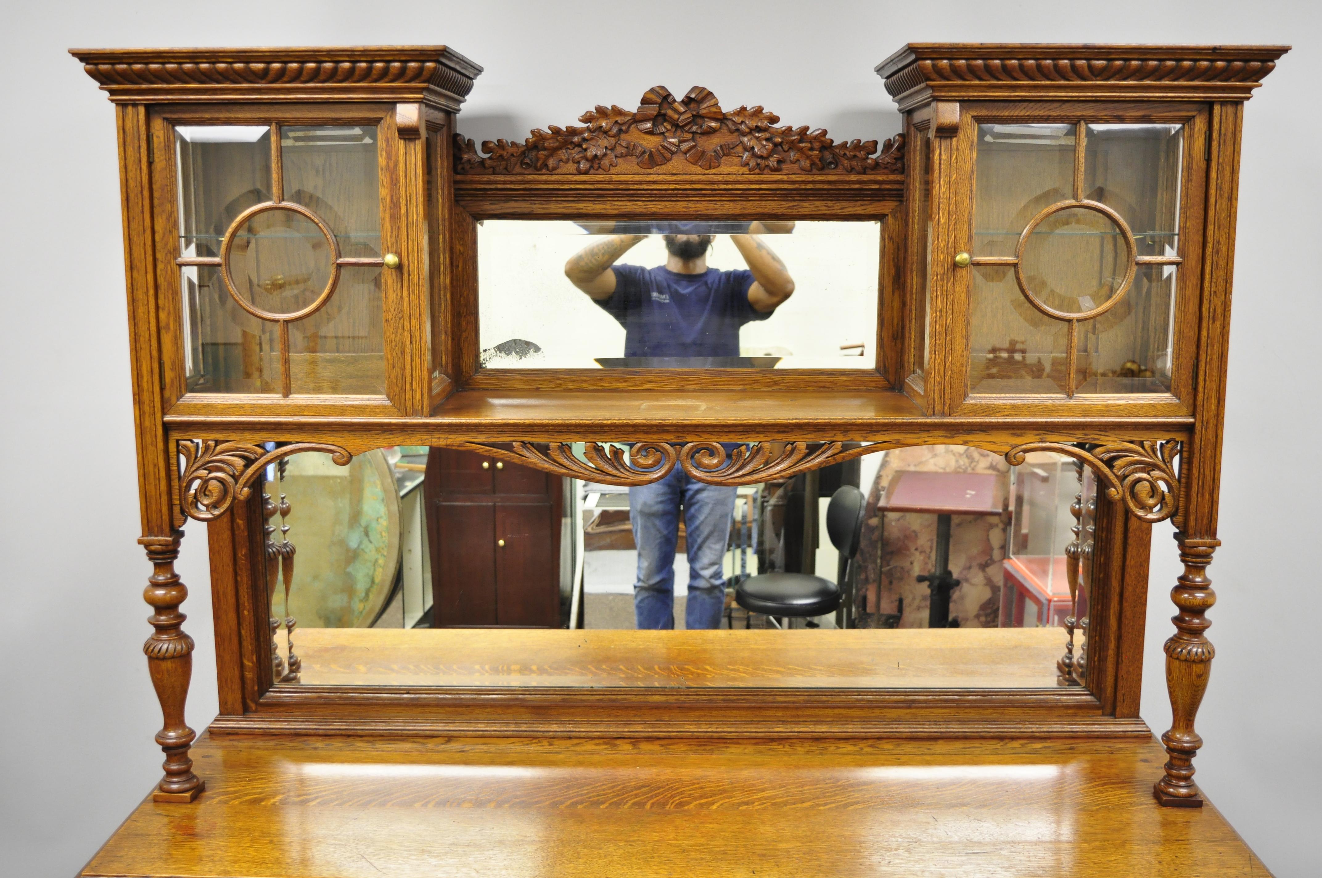 Antique Victorian French style carved oak sideboard buffet hutch with mirror back. Item features ornate brass hardware with female maiden faces, solid wood construction, beautiful wood grain, finely carved details, 2 part construction, 7 drawers,