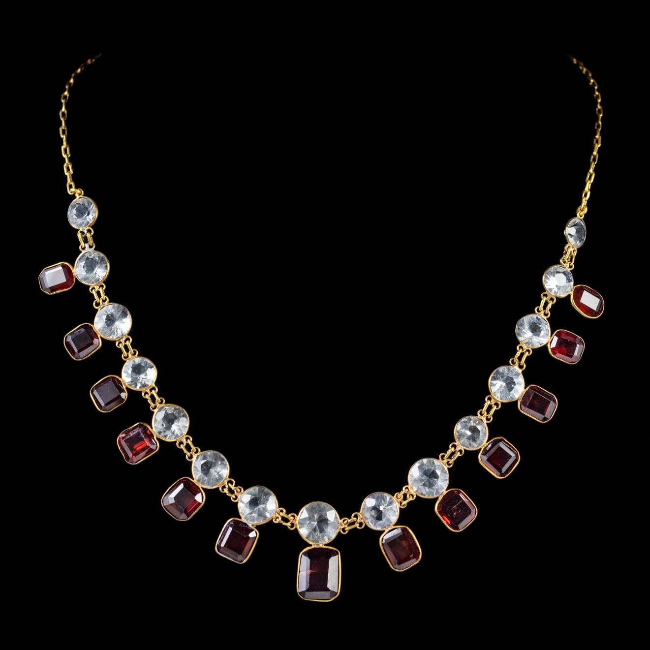 This stunning antique Victorian garland necklace features a line of sparkling white Quartz stones with deep red Garnets displayed underneath. 

The Garnet has been adored throughout history for its blazing red colour which hides beneath its dark