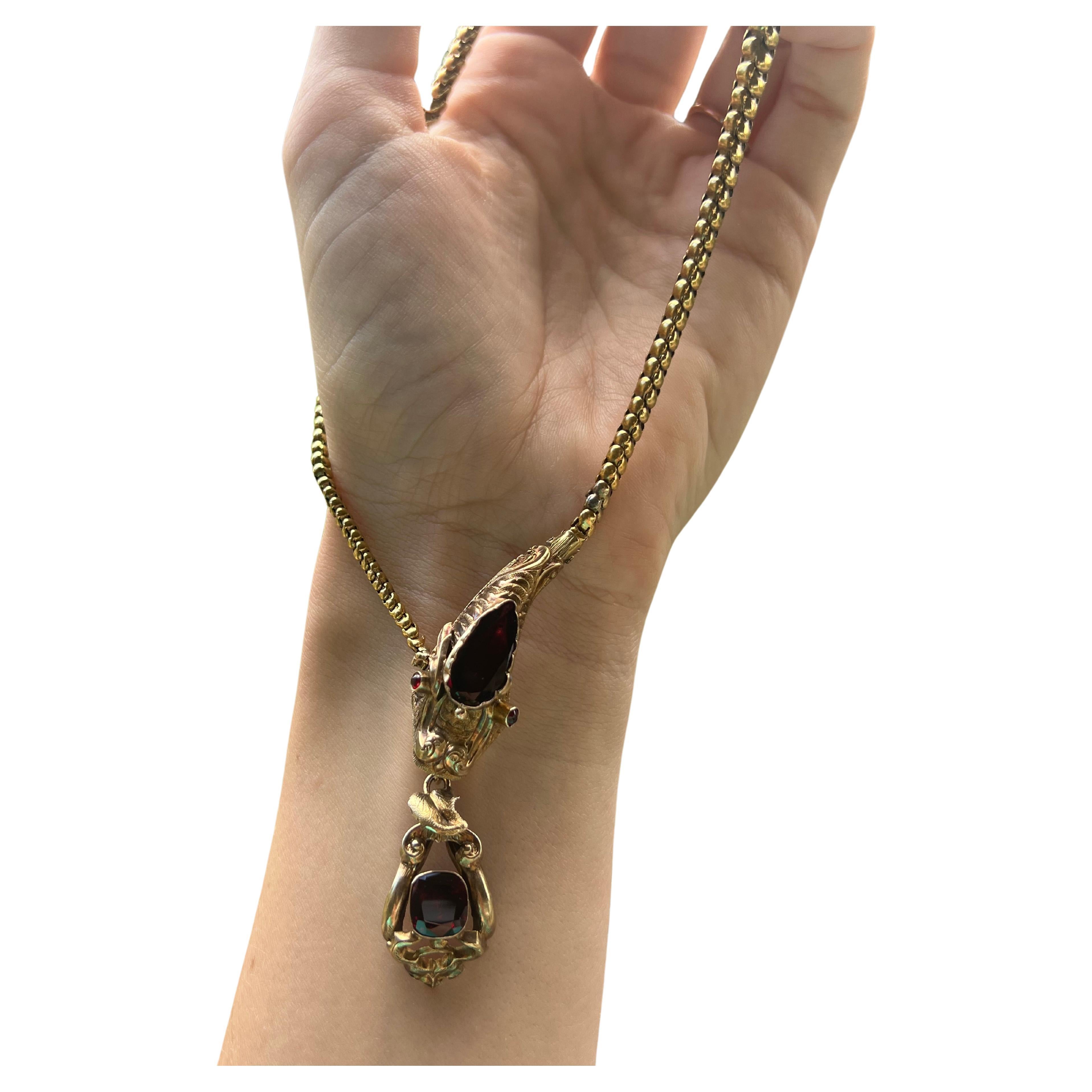 AN ANTIQUE VICTORIAN GARNET SET SNAKE NECKLACE. This necklace is in great condition and has beautiful features through the necklace.  The snake head set with a pear shaped garnet, an antique cushion cut, and two round cabochon cut garnet accent