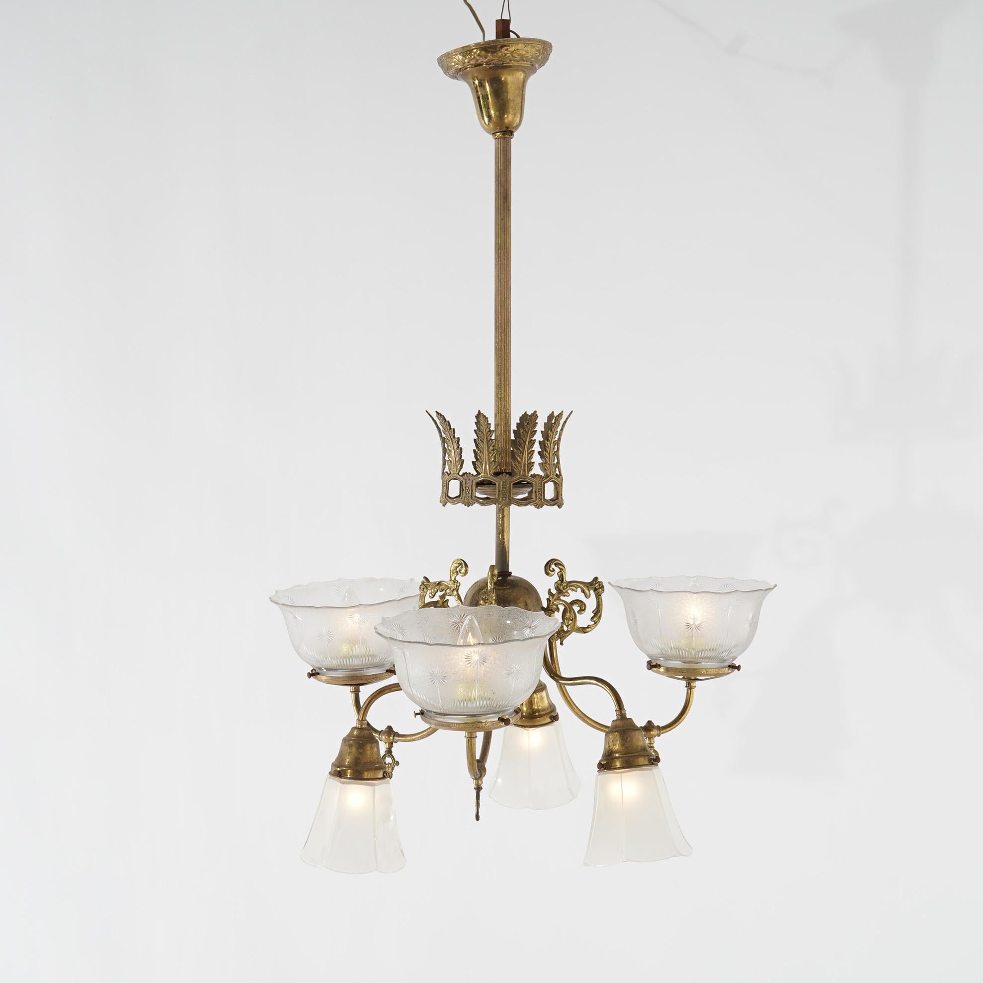 An antique Victorian gas and electric chandelier offers brass frame with scroll form up and down arms terminating in lights having glass shades, electrified, c1910

Measures - 36