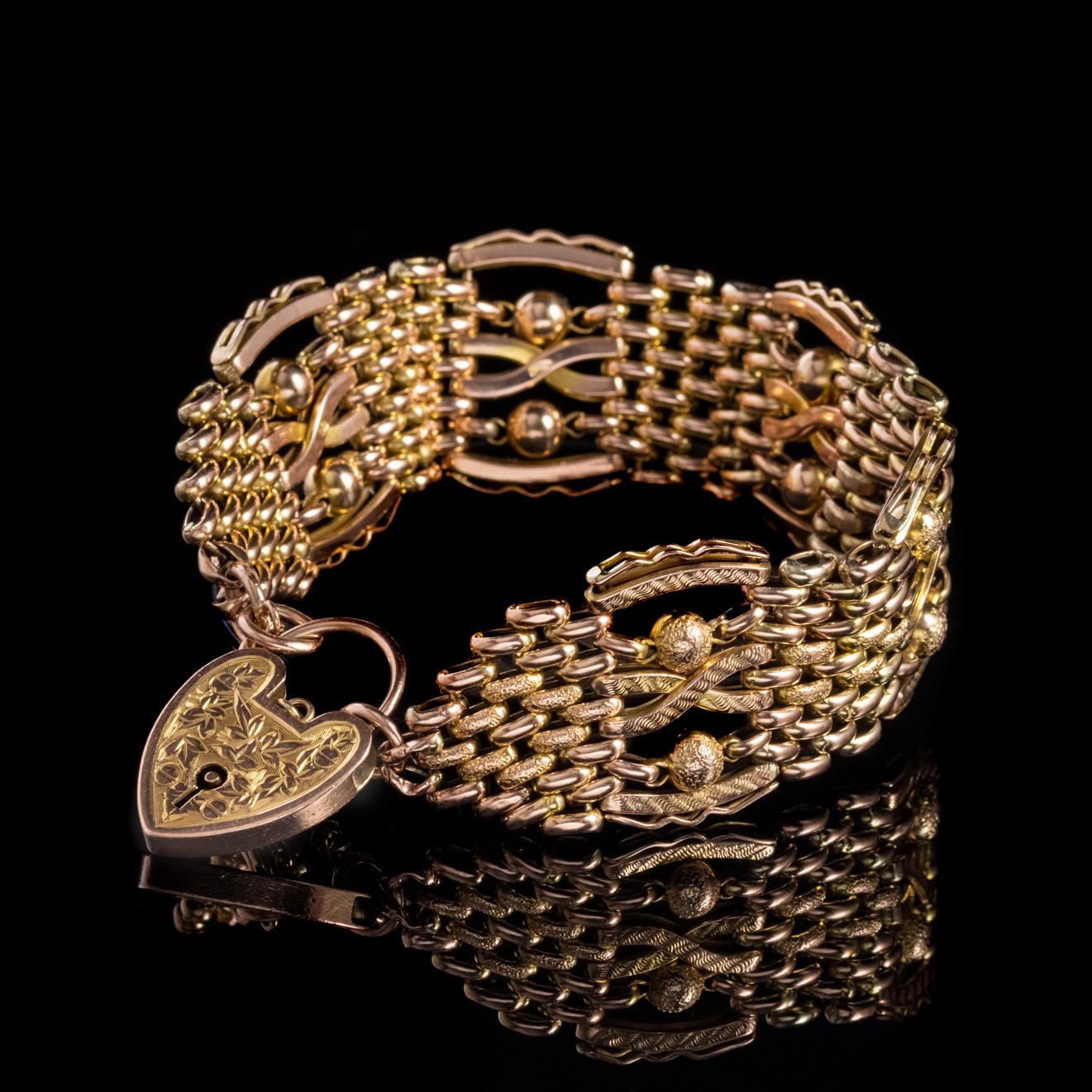 A grand Antique Victorian gate bracelet made up of fancy solid 9ct Rose Gold links with textured detailing and ornate Golden balls. 

The piece is held together by a safety chain and a wonderful solid Gold heart padlock engraved with Ivy on the