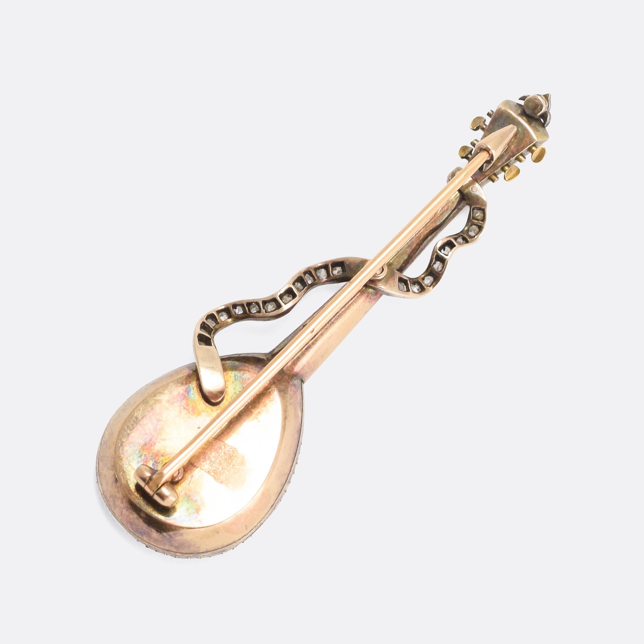 An absolutely stunning antique brooch modelled as a four string Domra. The almond-shaped body is bordered with rose cut diamonds, and set with natural pearls and rubies - with delicate blue enamel detailing. With a diamond-set strap and further