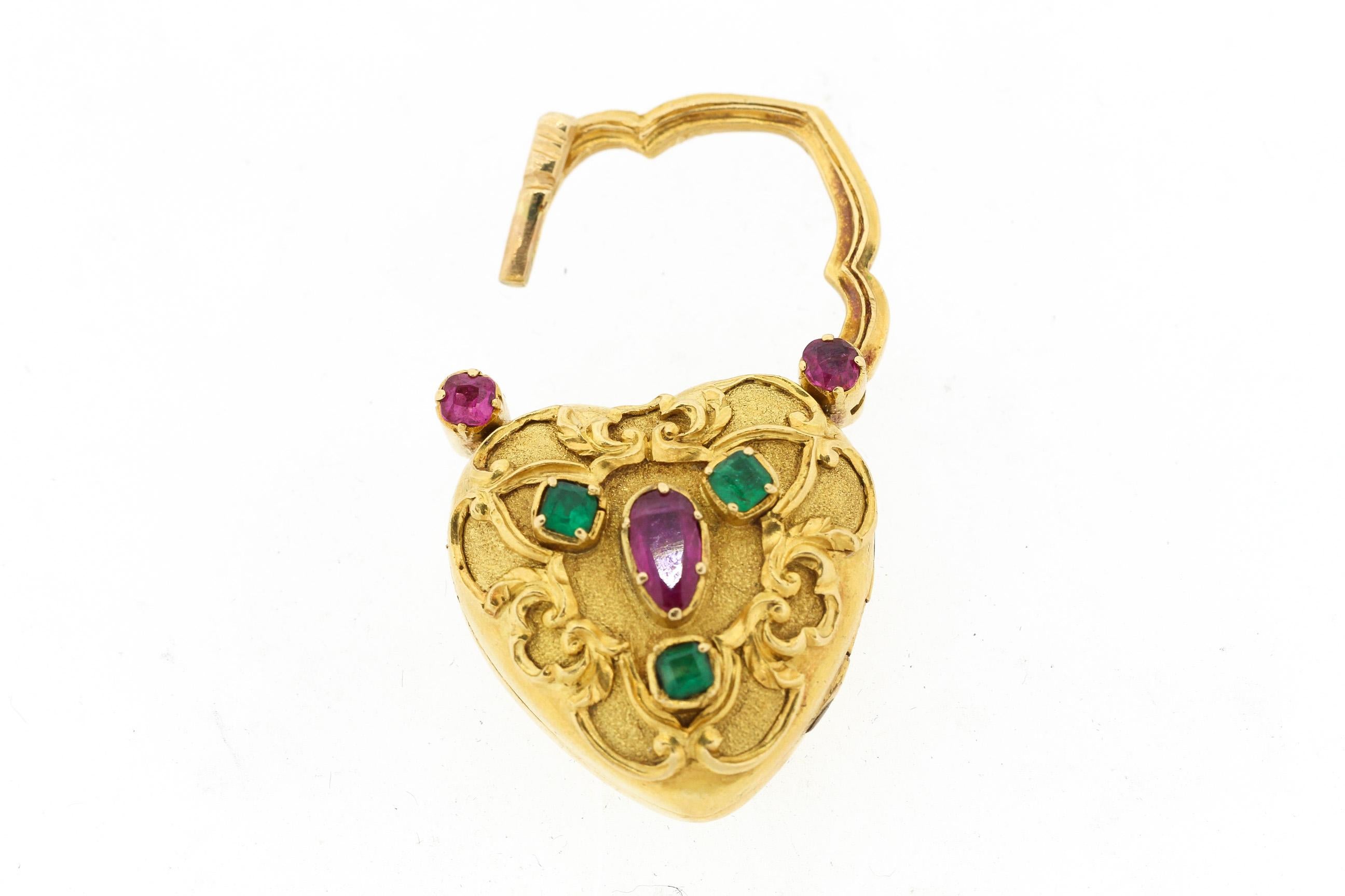 A charming Victorian repousse heart locket with padlock top set with emeralds and rubies, circa 1880. This beautifully rendered padlock locket is made in 18k gold and has high relief scroll work, and bright rubies and emeralds. The inside opens to