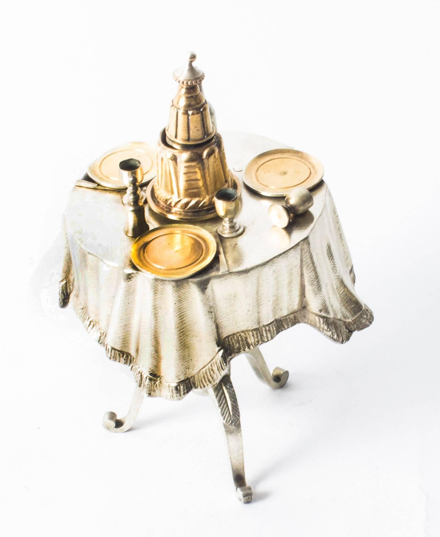 A charming Victorian silver plated and gilt bronze call bell in the form of a set dining table. 

The dressed table features a central bell push in the form a cake with a bottle of wine, three plate and wine glasses on a circular table top that