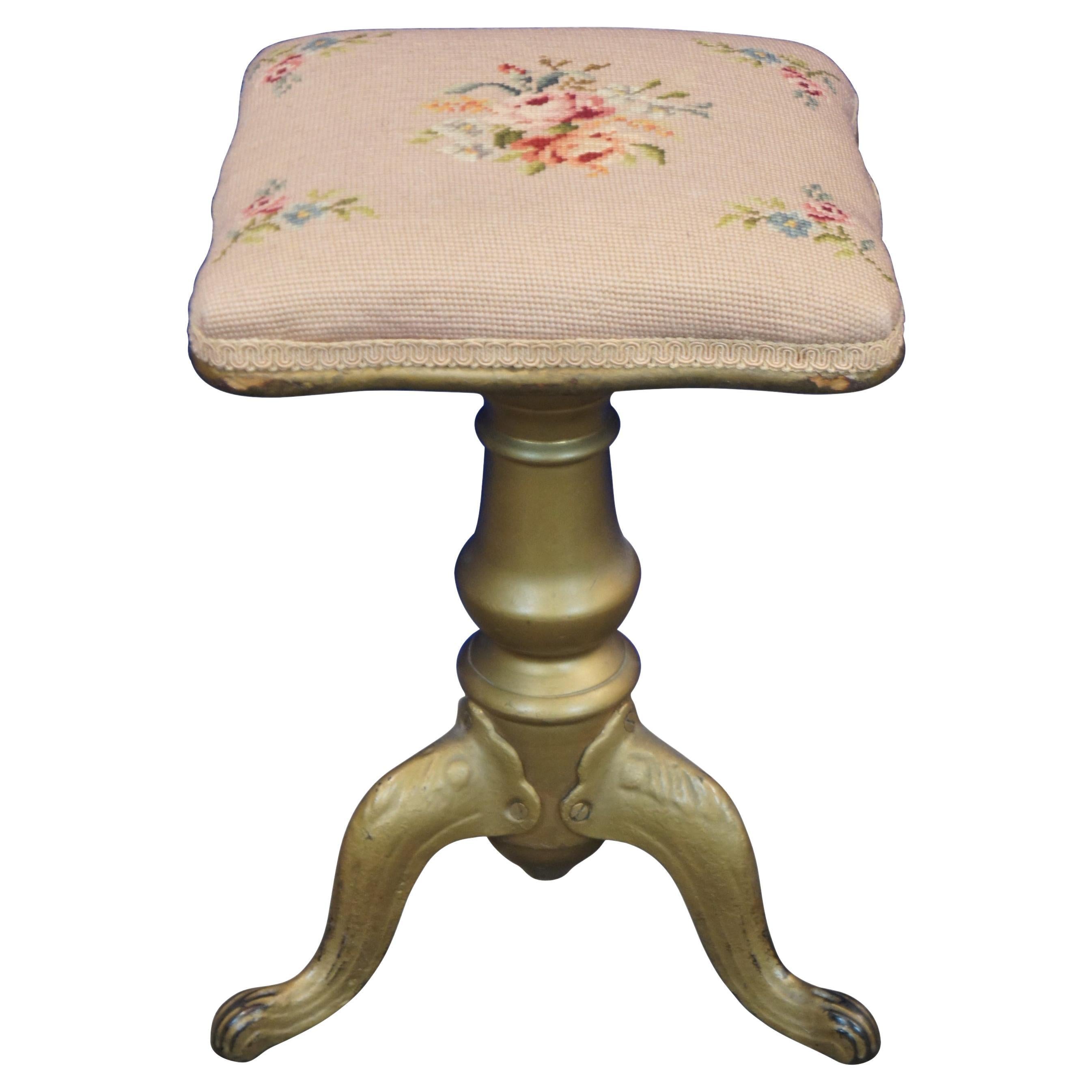 Antique Victorian piano stool with a wood and metal baluster shaped base with cabriole paw feet, painted gold, and a square adjustable height seat covered in pink floral needlepoint.

Measures: 12” x 12” x 22” / Lowest Height – 18.5” (Width x
