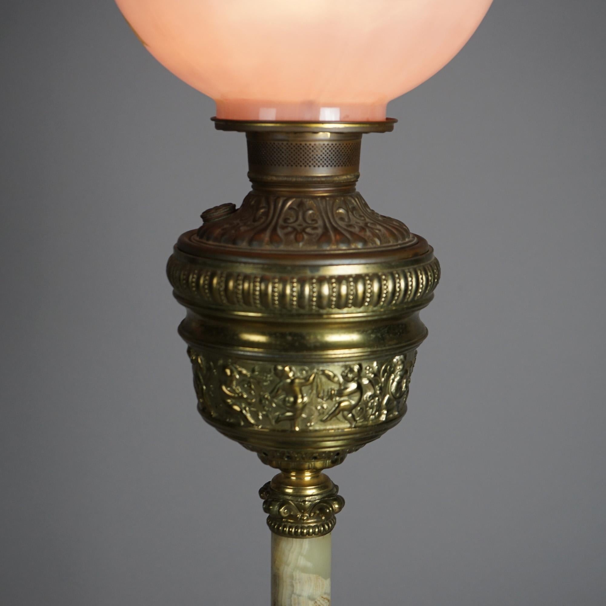 An antique Victorian parlor lamp offers hand painted floral glass shade over gilt metal base having font with embossed dancing cherubs, onyx column, and seated on footed base; electrified; c1880

Measures - 36.25