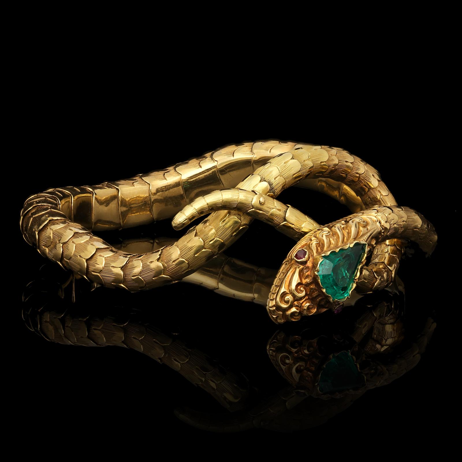 A beautiful Victorian gold and emerald snake bracelet c.1890, the long sinuous body formed of multiple highly articulated overlapping sections of finely engraved scales in 18ct gold, the head set with a wonderful intense green kite-shaped emerald