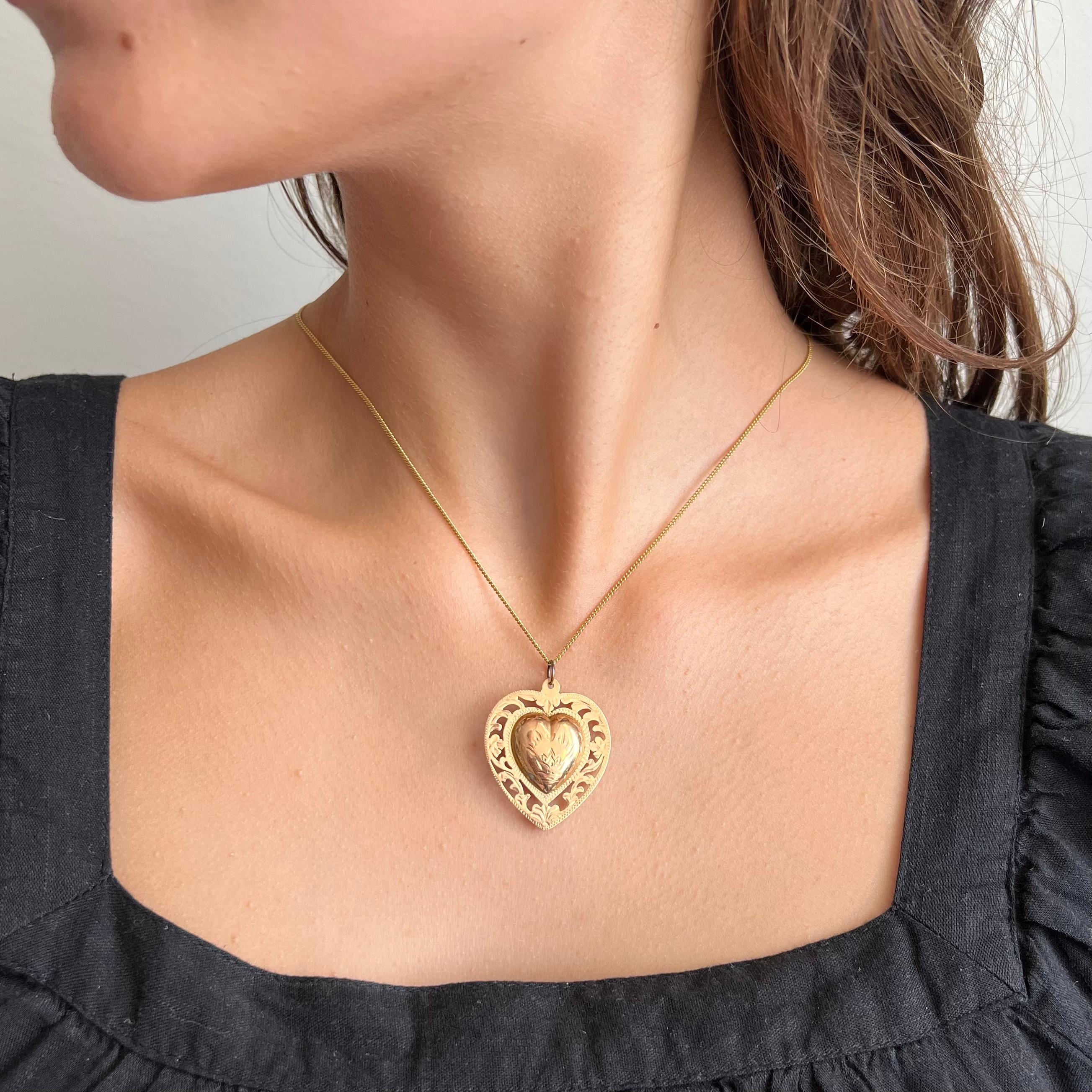 A large Victorian 14 karat yellow gold locket heart pendant. This lovely heart design features an openwork border with a scrolling floral pattern of leaves and flowers. The center of the puffy heart has beautiful engraved details. The back of the