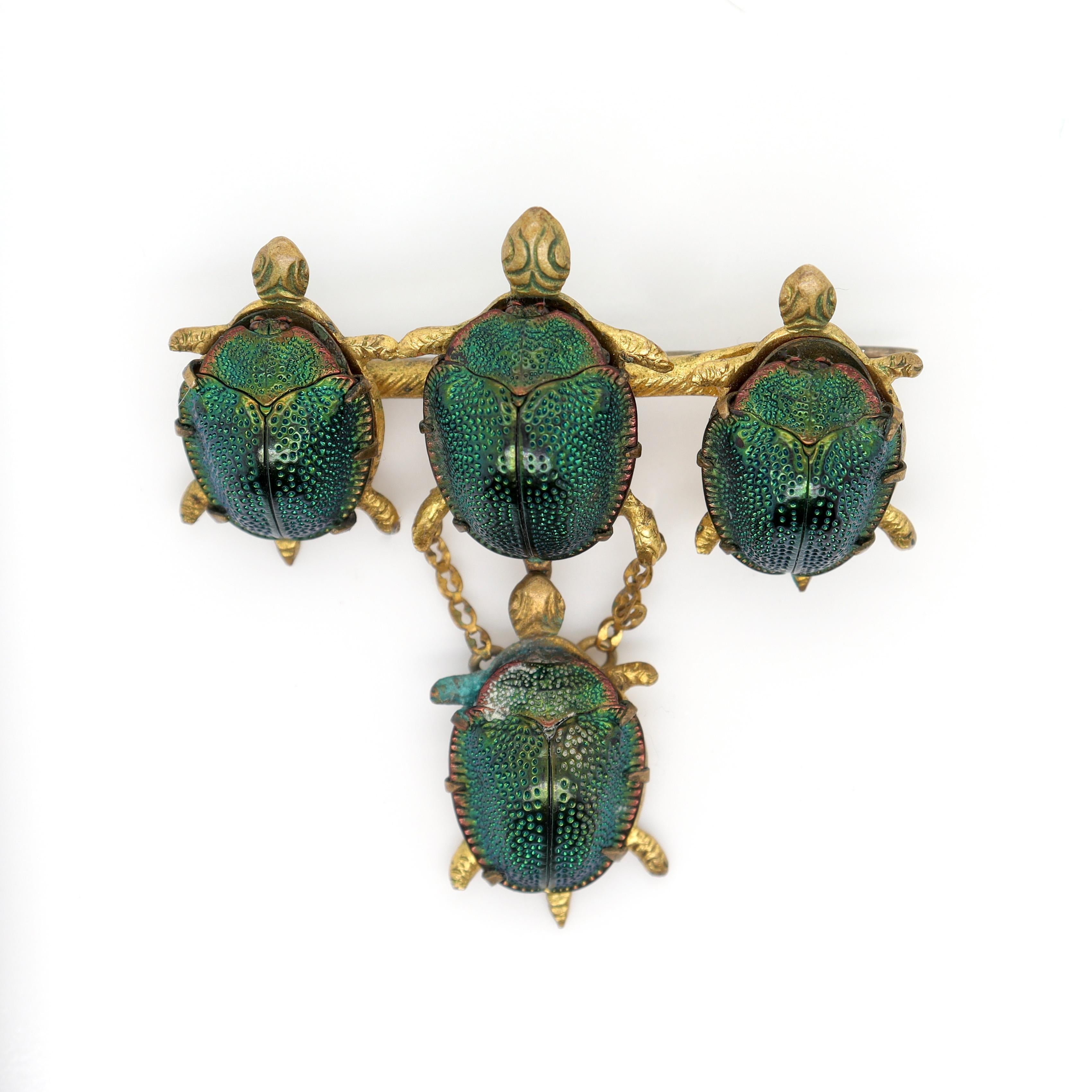 A fine antique Victorian gold filled brooch.

Consisting of 3 turtles mounted on a bar pin supporting a fourth suspended by 2 fine link chains.

Each turtle is set with a natural scarab beetle shell as its the turtle shell. 

Gold-filled and