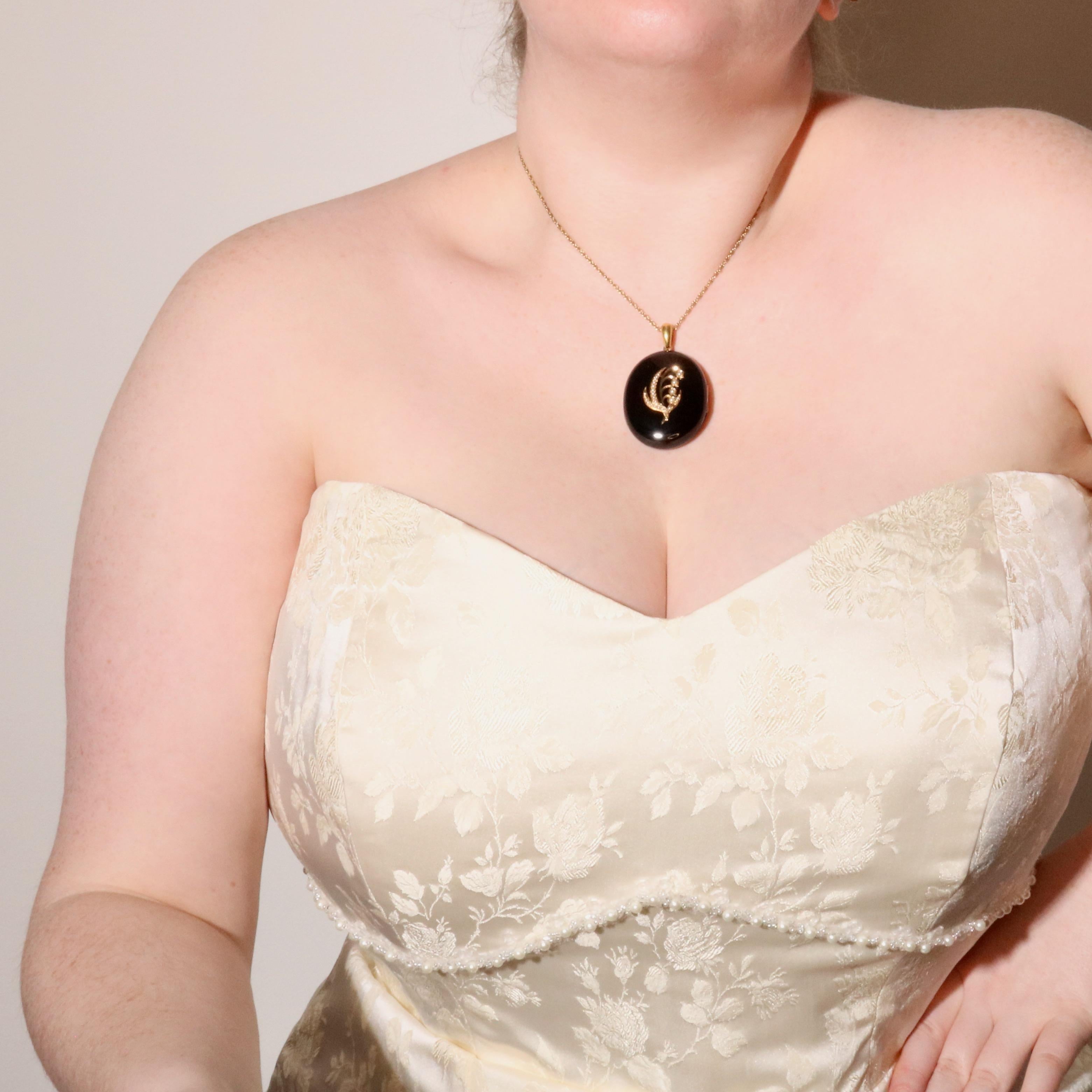 A Victorian yellow gold, black paste, and seed pearl locket, comprising two oval cabochons of black paste, twenty-two seed pearls, set in 9 karat yellow gold, with an 18 karat yellow gold bale.   

This symbolic Victorian mourning locket is