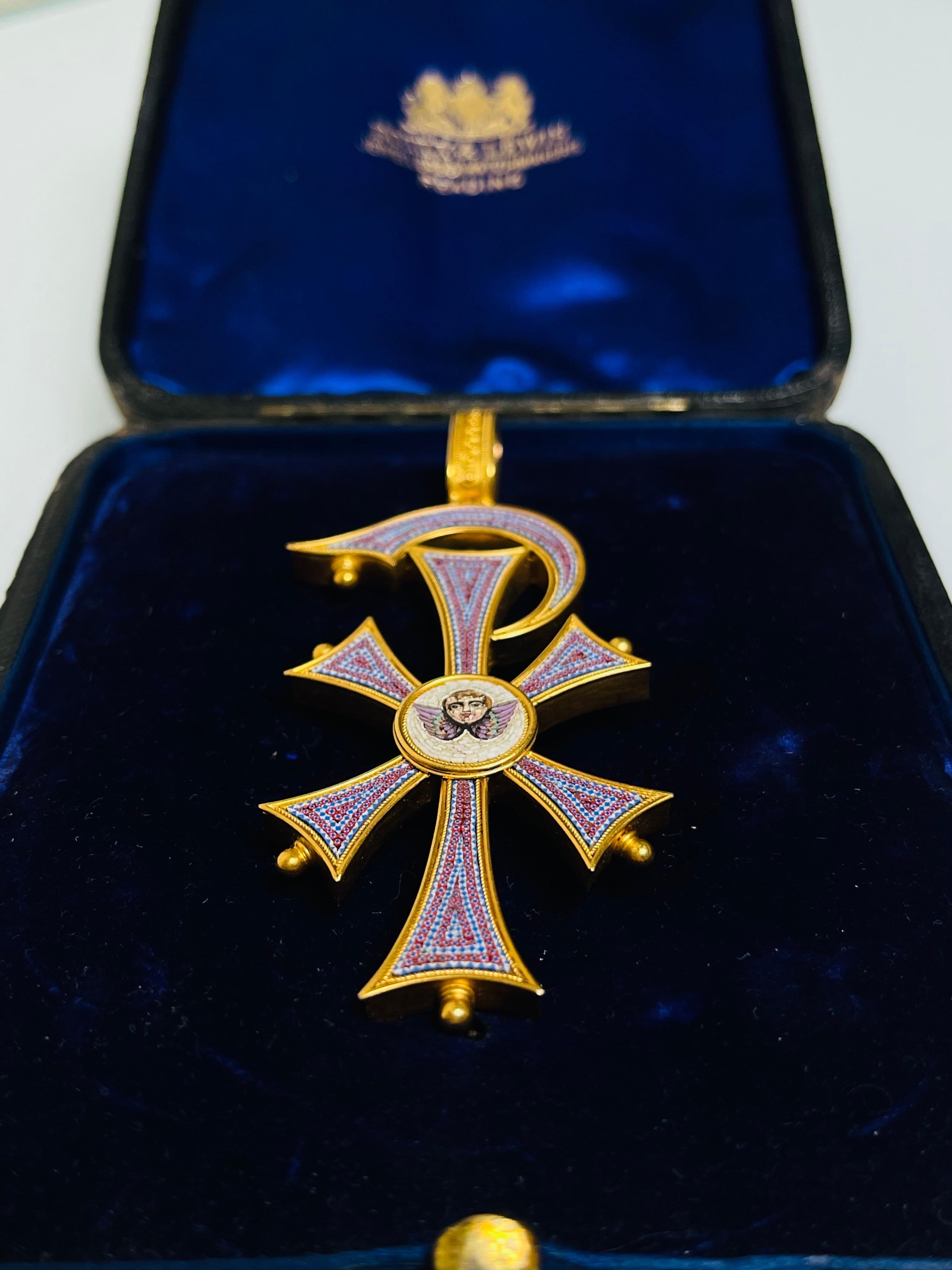 An exquisite C 1860 Italian micromosaic cross pendant, possibly commissioned in the Papal workshops and shaped in the form of the Chi-Rho - a symbol of Christ. The center is embellished with a round micromosaic plaque depicting a winged cherub—a