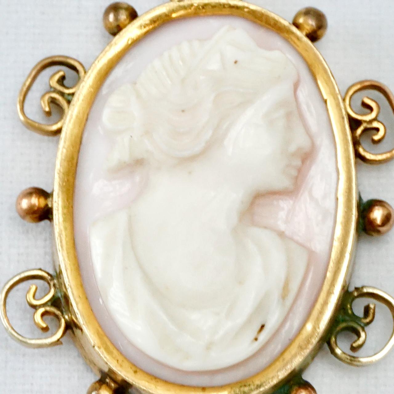 Beautiful antique carved angel skin coral cameo pendant of a lady, in a decorative gold plated setting. Measuring 3.3 cm / 1.3 inches by 2.4 cm / .9 inch. There is wear to the gold plating.

This is a lovely angel skin cameo pendant from the